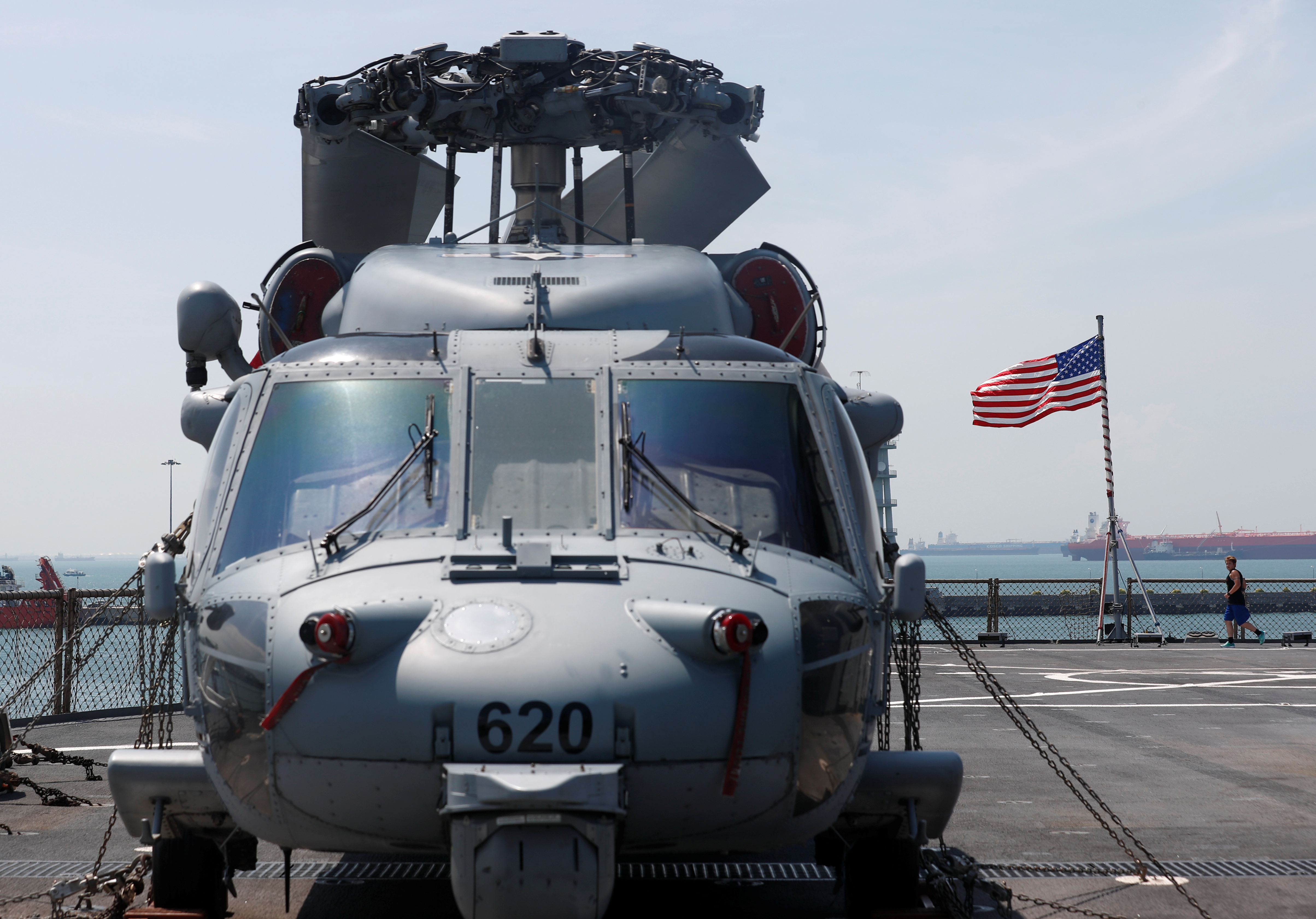 A serviceman jogs past a Sikorsky SH-60 Seahawk helicopter onboard the USS Blue Ridge (LCC 19) in Singapore