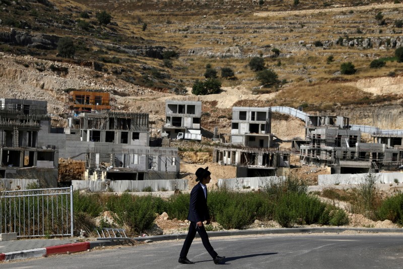 A Jewish settler walks past Israeli settlement construction sites around Givat Zeev and Ramat Givat Zeev in the Israeli-occupied West Bank