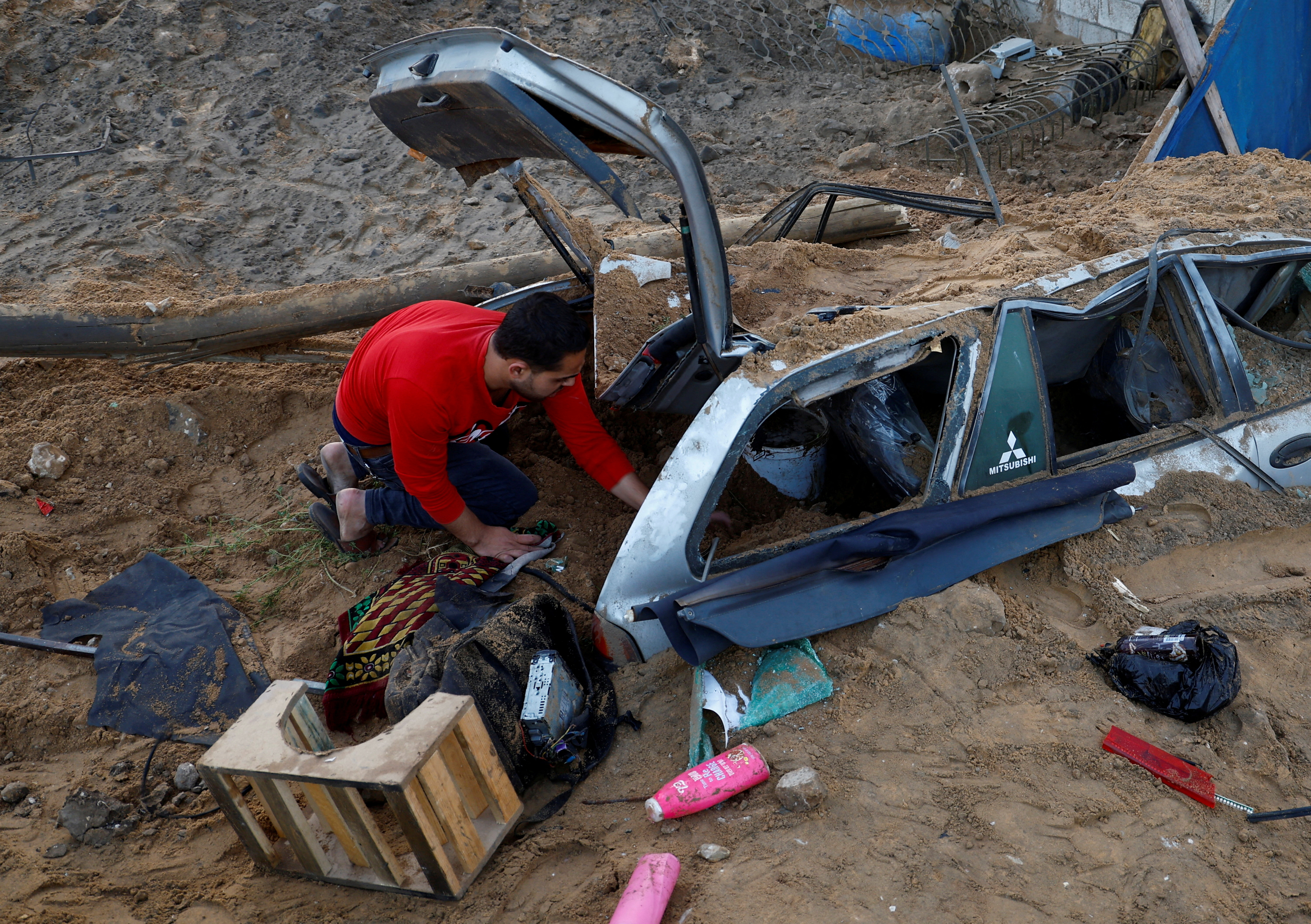 A Palestinian man Muhanad Abu Neama checks the damage of his car, in the aftermath of Israeli airstrikes in Gaza City