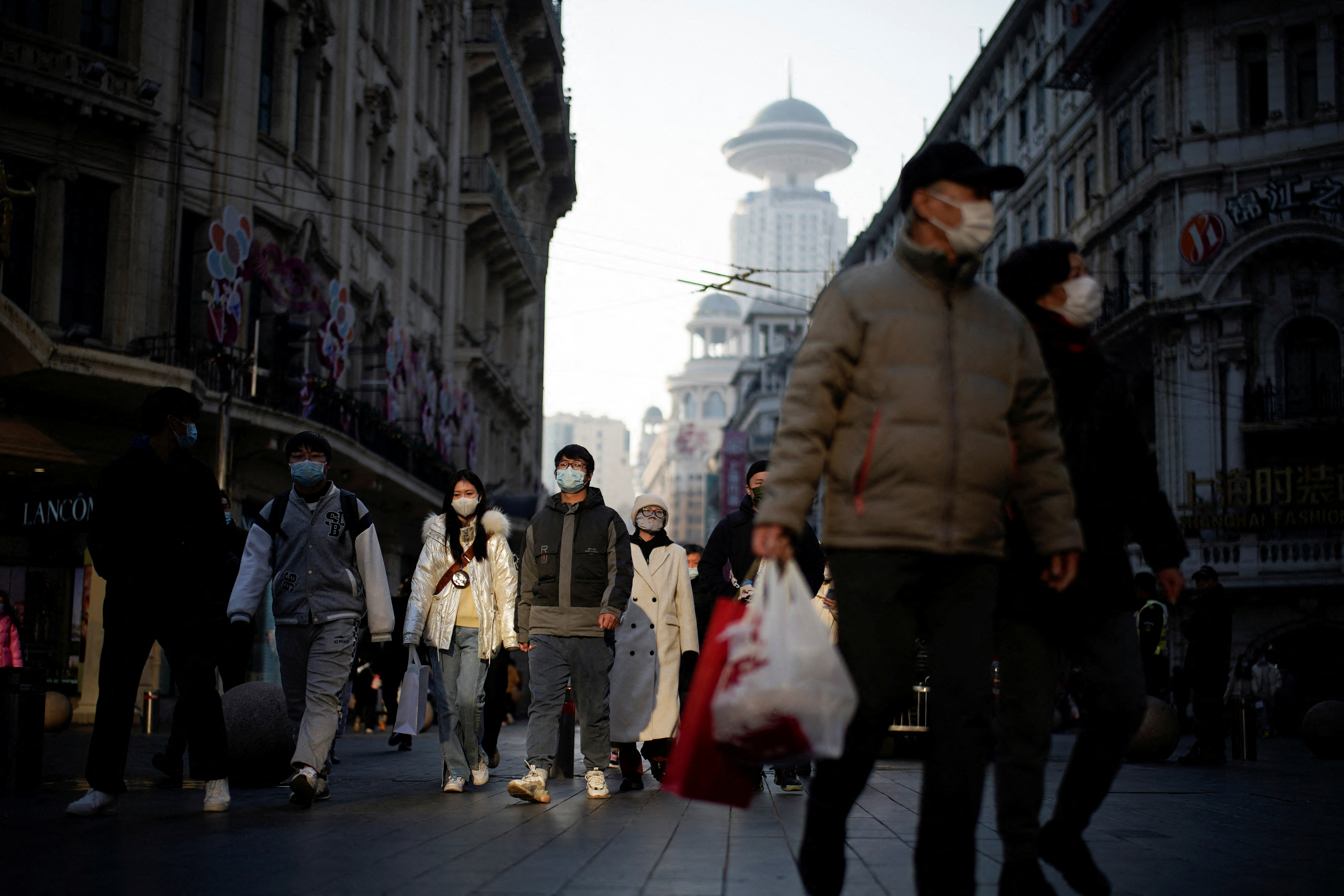 People wearing protective face masks walk on a street, following new cases of the coronavirus disease (COVID-19), in Shanghai, China, December 30, 2021. REUTERS/Aly Song