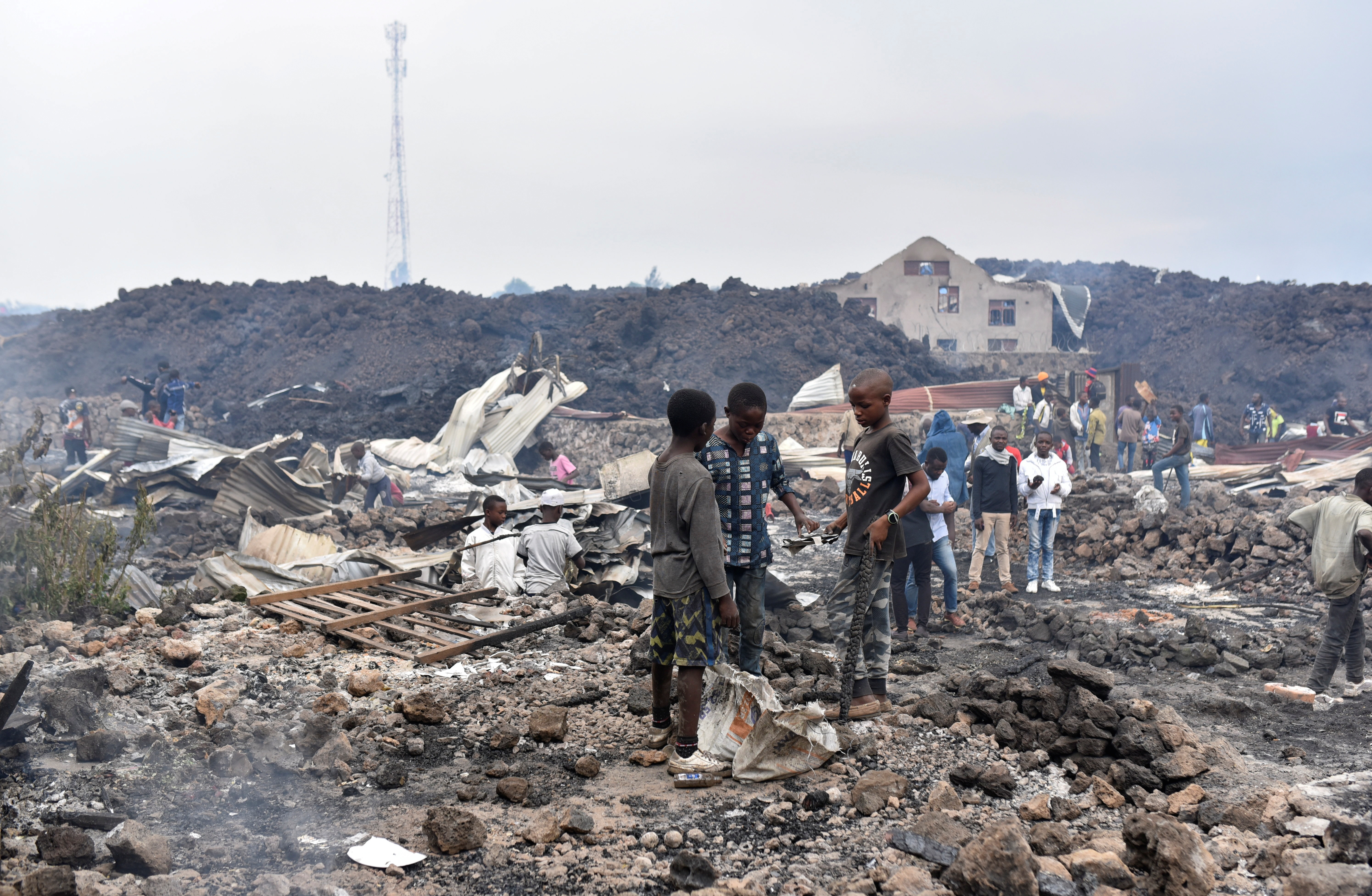 Residents pick up remains of their destroyed homes from the smouldering lava deposited by the eruption of Mount Nyiragongo volcano near Goma