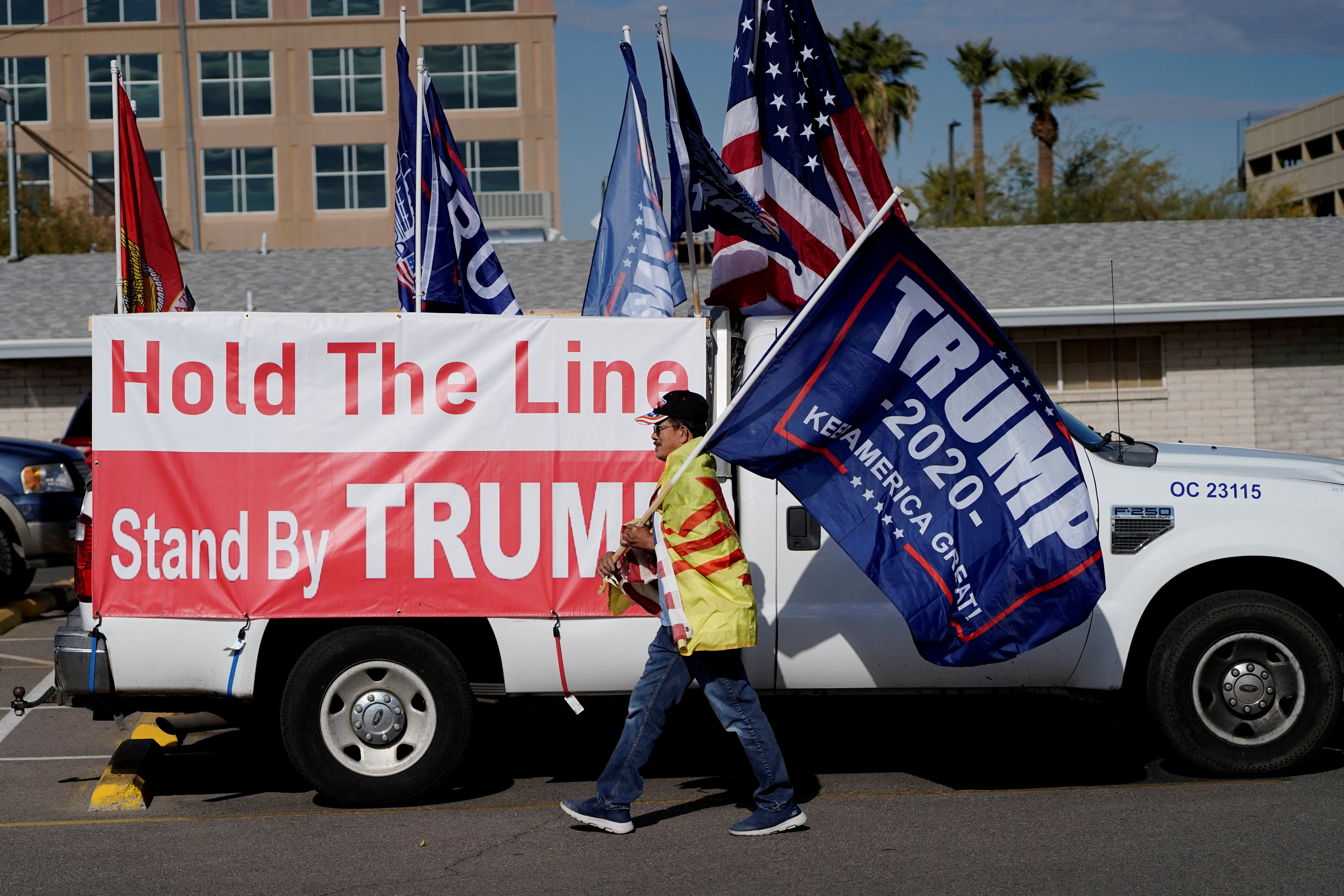 A protestor caries a "Trump 2020" flag as Arizona electors gather to cast their votes for the U.S. presidential election in Phoenix