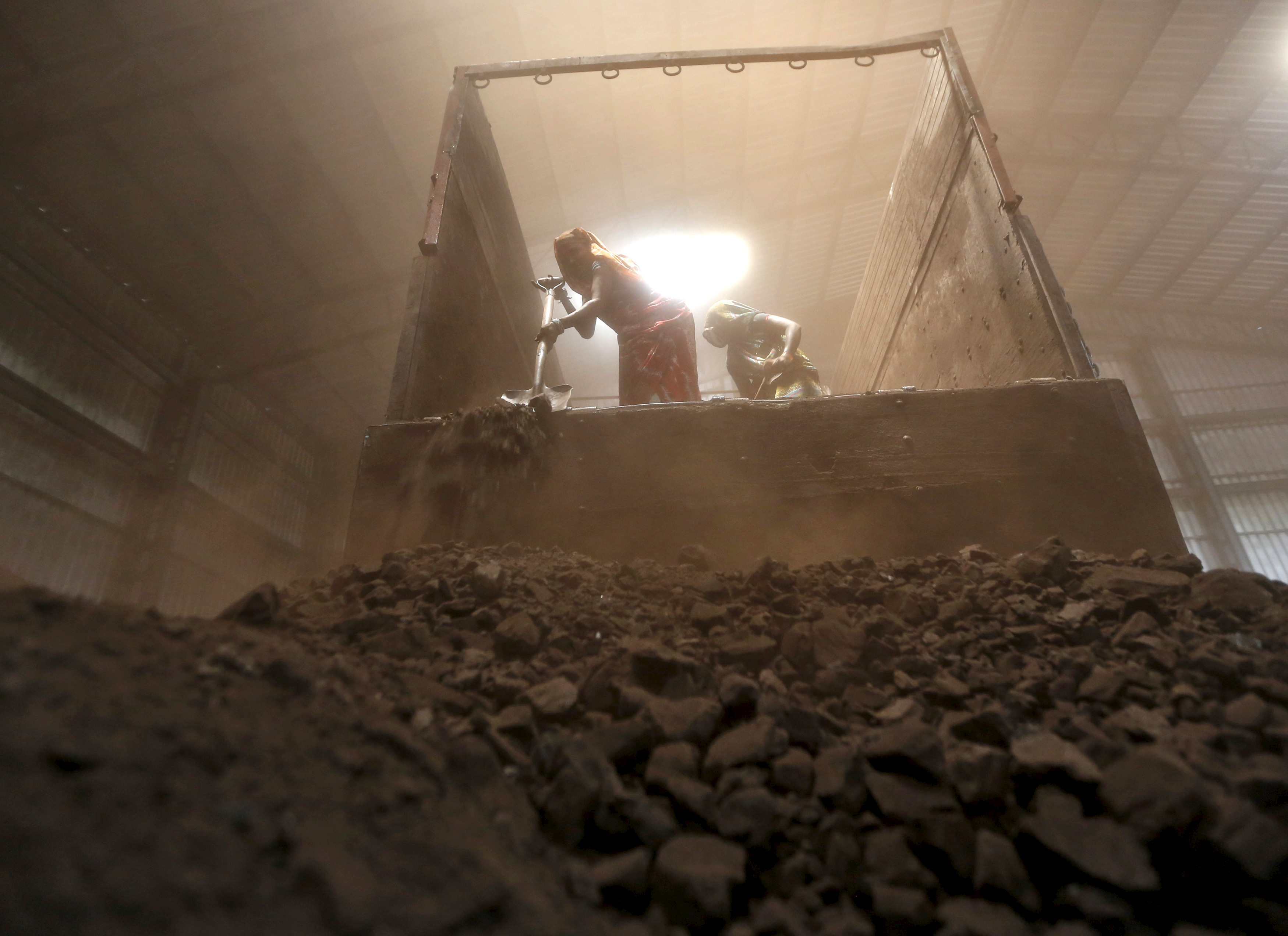 Workers unload coal from supply truck at yard on outskirts of western Indian city of Ahmedabad