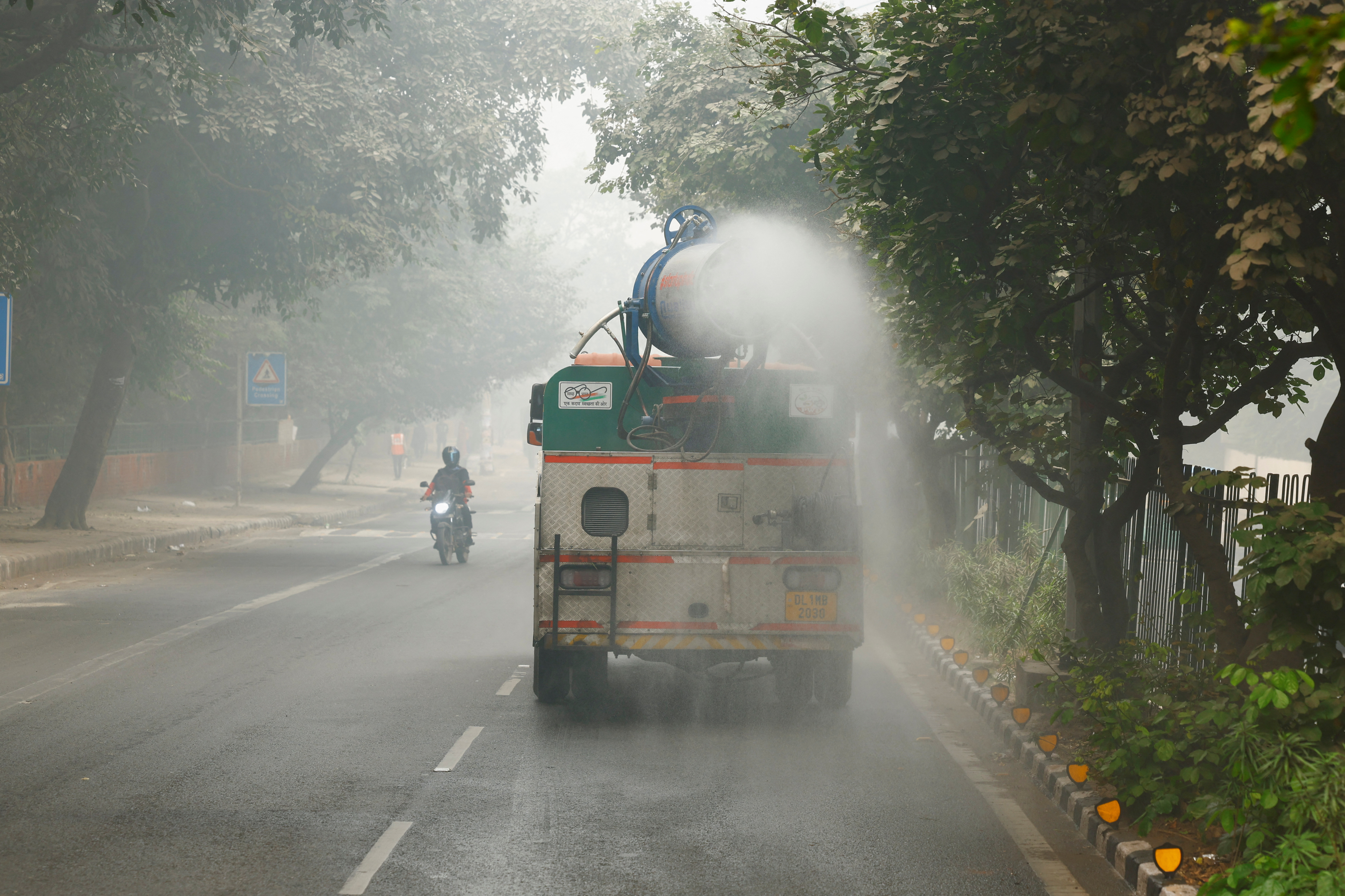 A vehicle sprays water to curb dust and pollution as the sky is enveloped with smog after Delhi's air quality turned "hazardous", in New Delhi