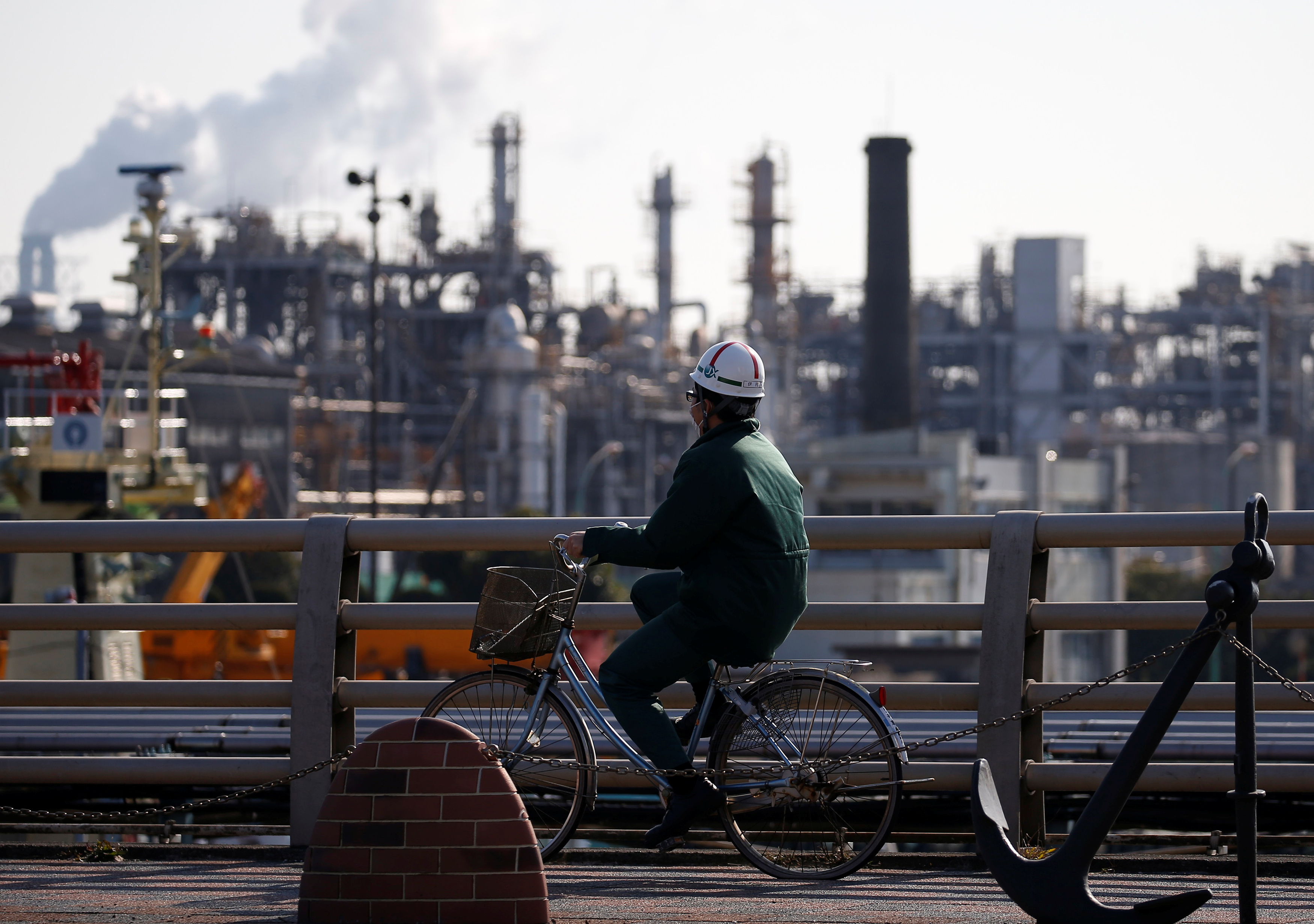 A worker cycles near a factory at the Keihin industrial zone in Kawasaki
