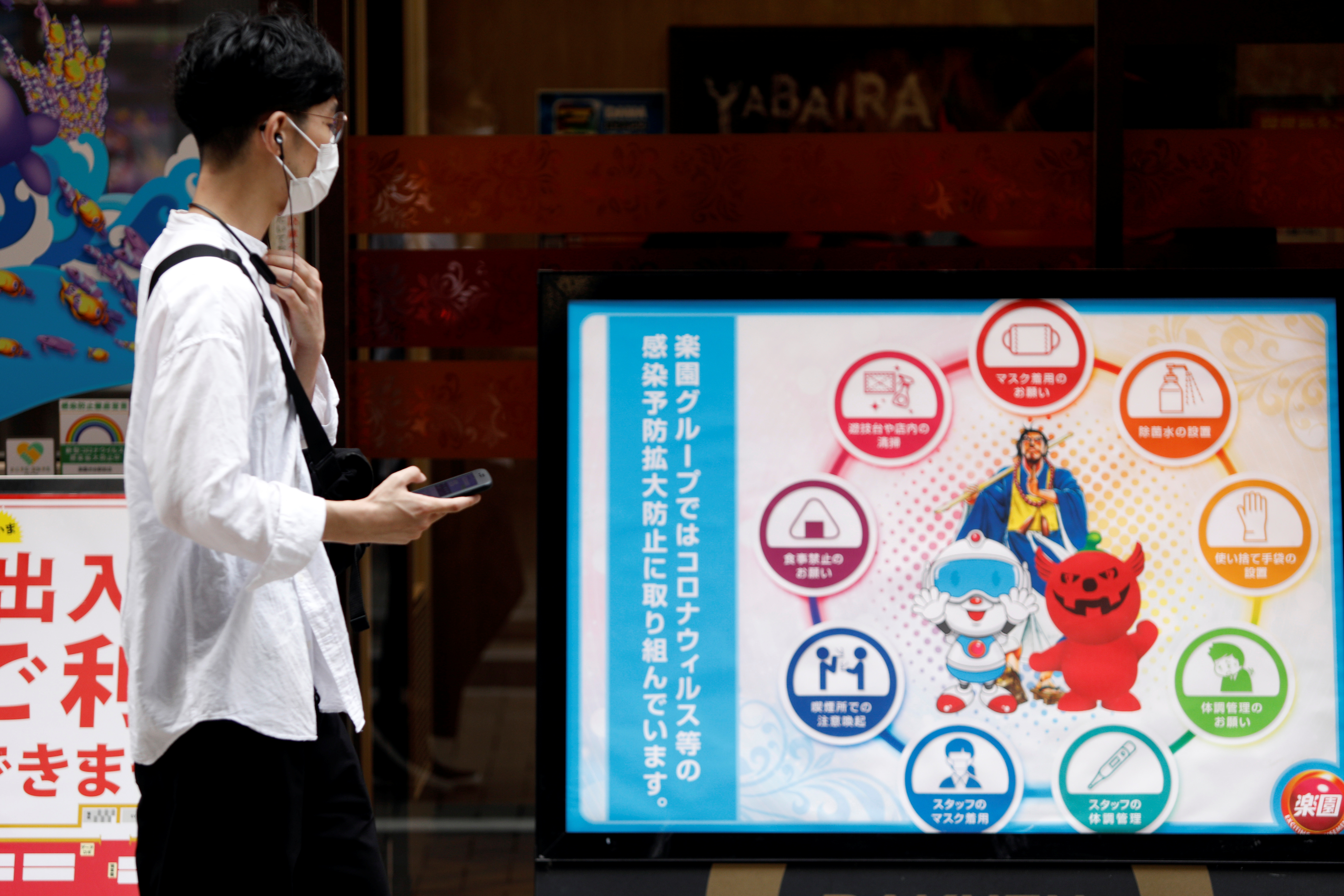Man looks at infection prevention information in Shibuya shopping area, in Tokyo
