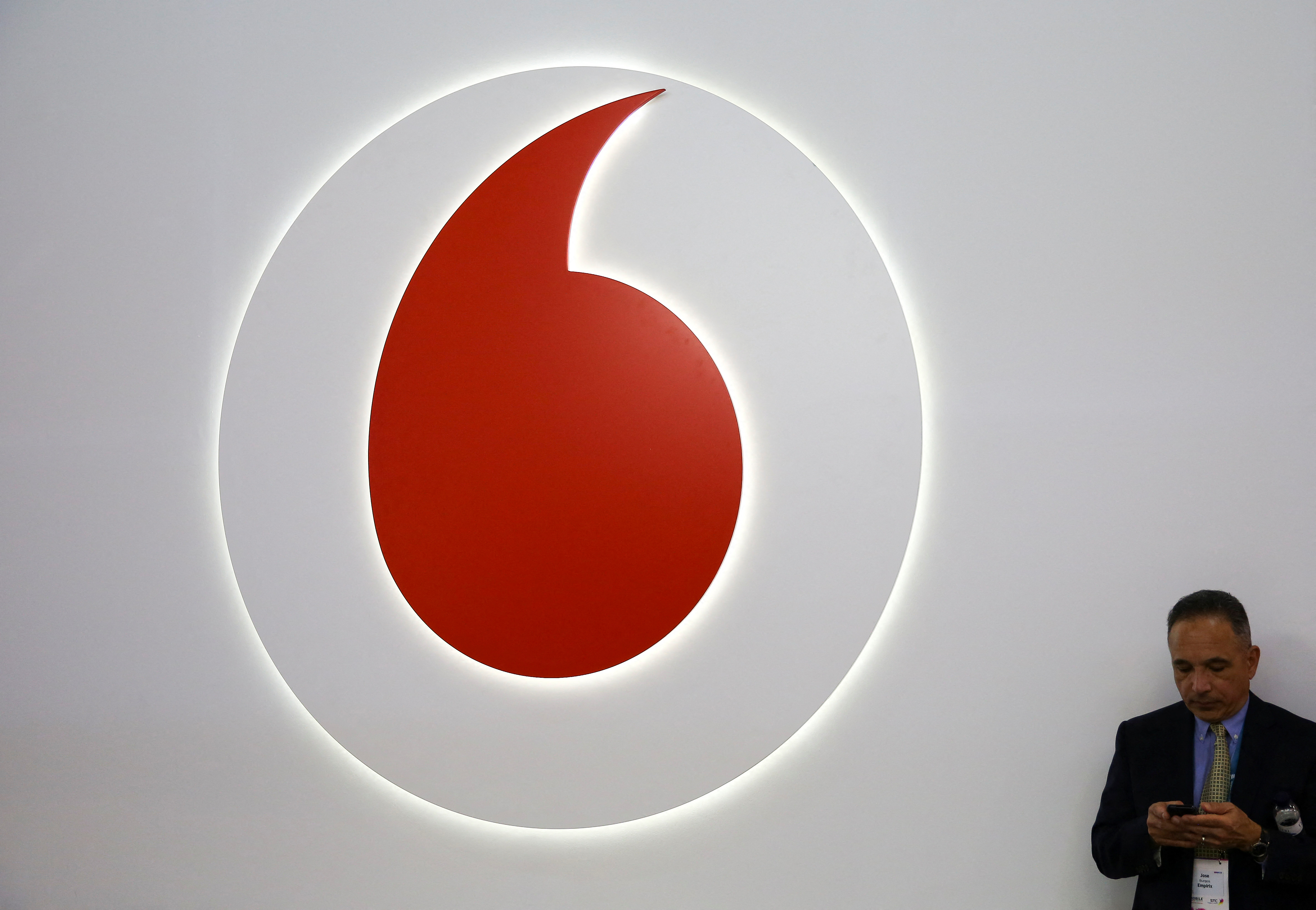 A man looks at his phone next to a Vodafone logo at the Mobile World Congress in Barcelona