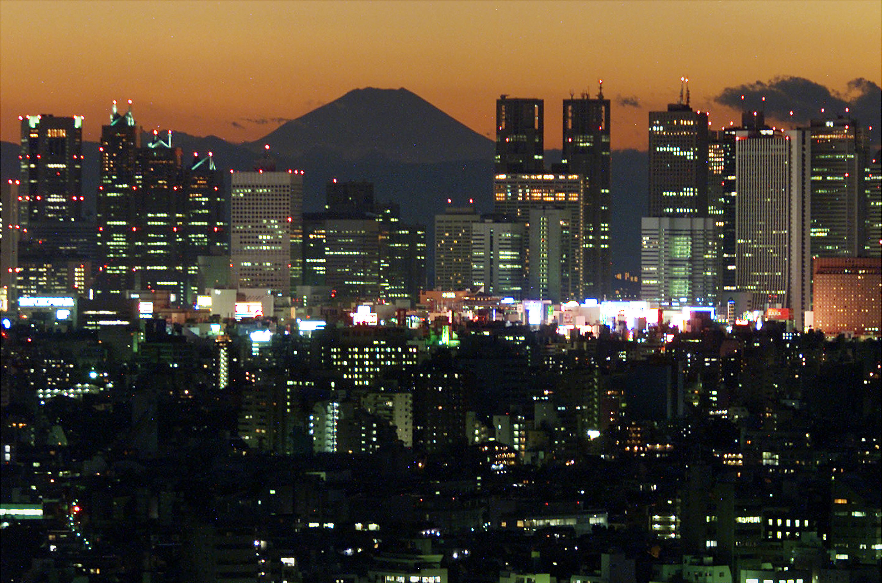 Japan's highest peak Mt Fuji is seen at dusk over the Shinjuki business district skyscraper in Tokyo..