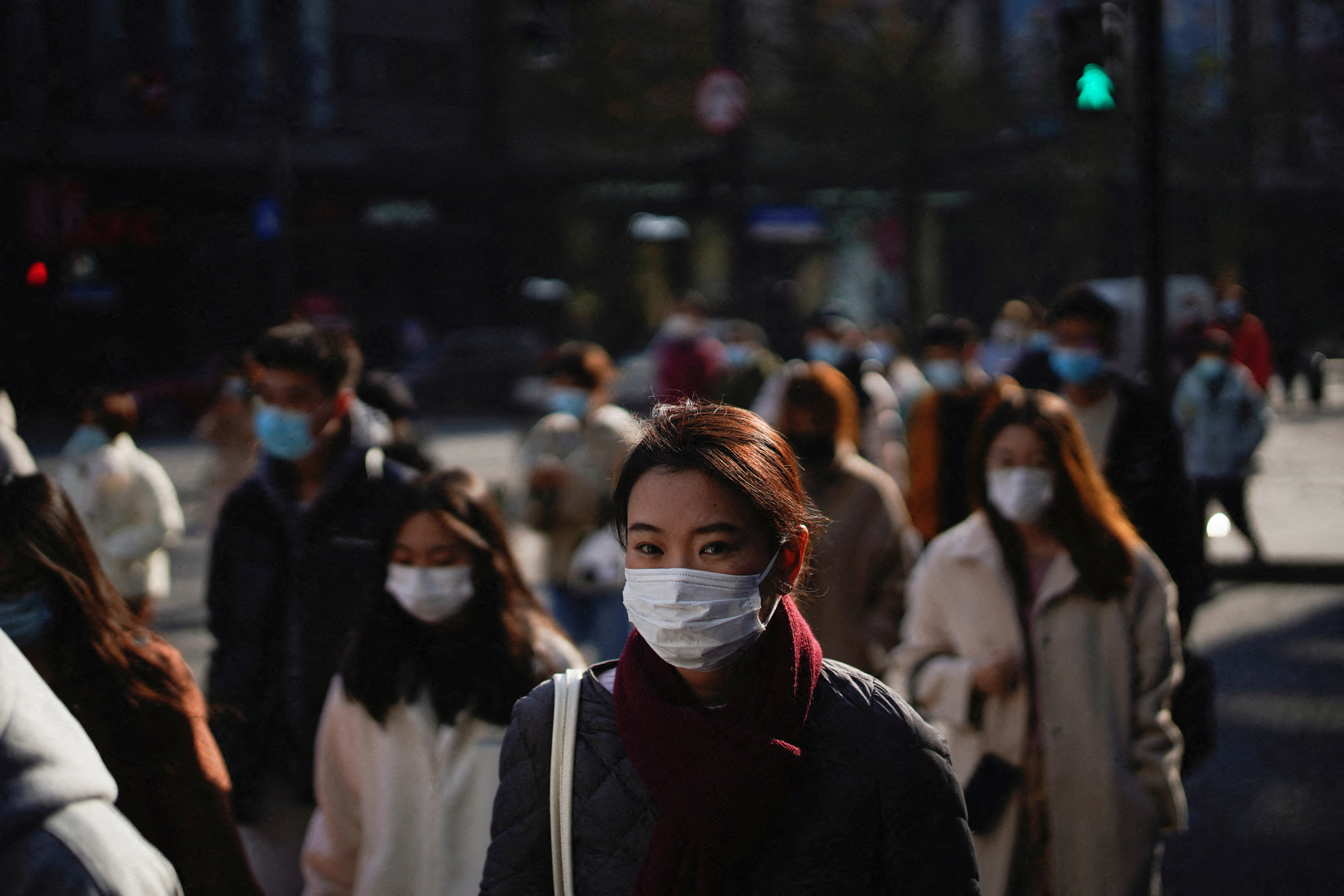 People wearing protective masks walk on a street, following new cases of the coronavirus disease (COVID-19), in Shanghai, China, December 20, 2021. REUTERS/Aly Song/File Photo