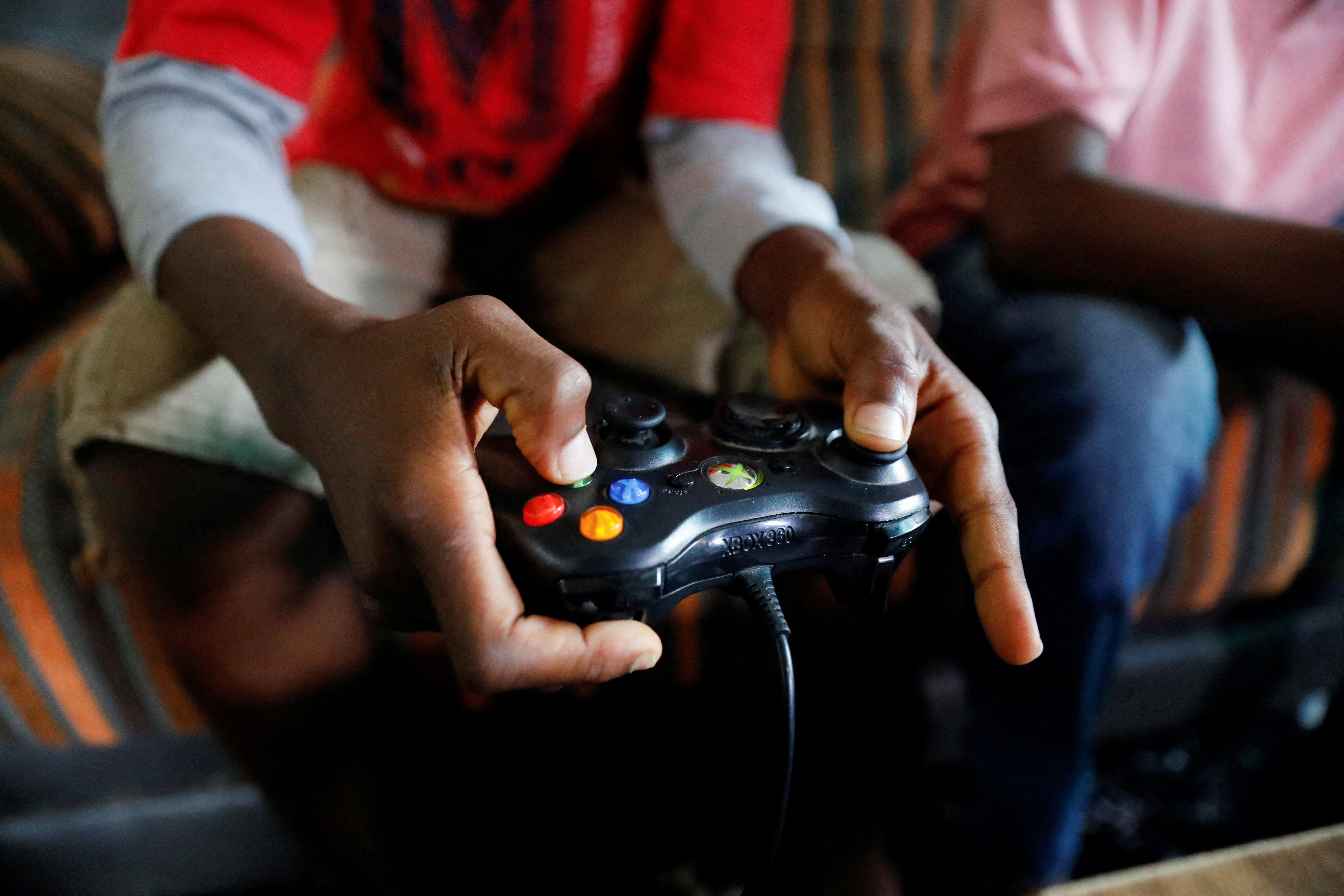 Udom Idongesit, 13, uses a gaming controller as he plays a Vikseen Virtual video game, in his home in Ogun State