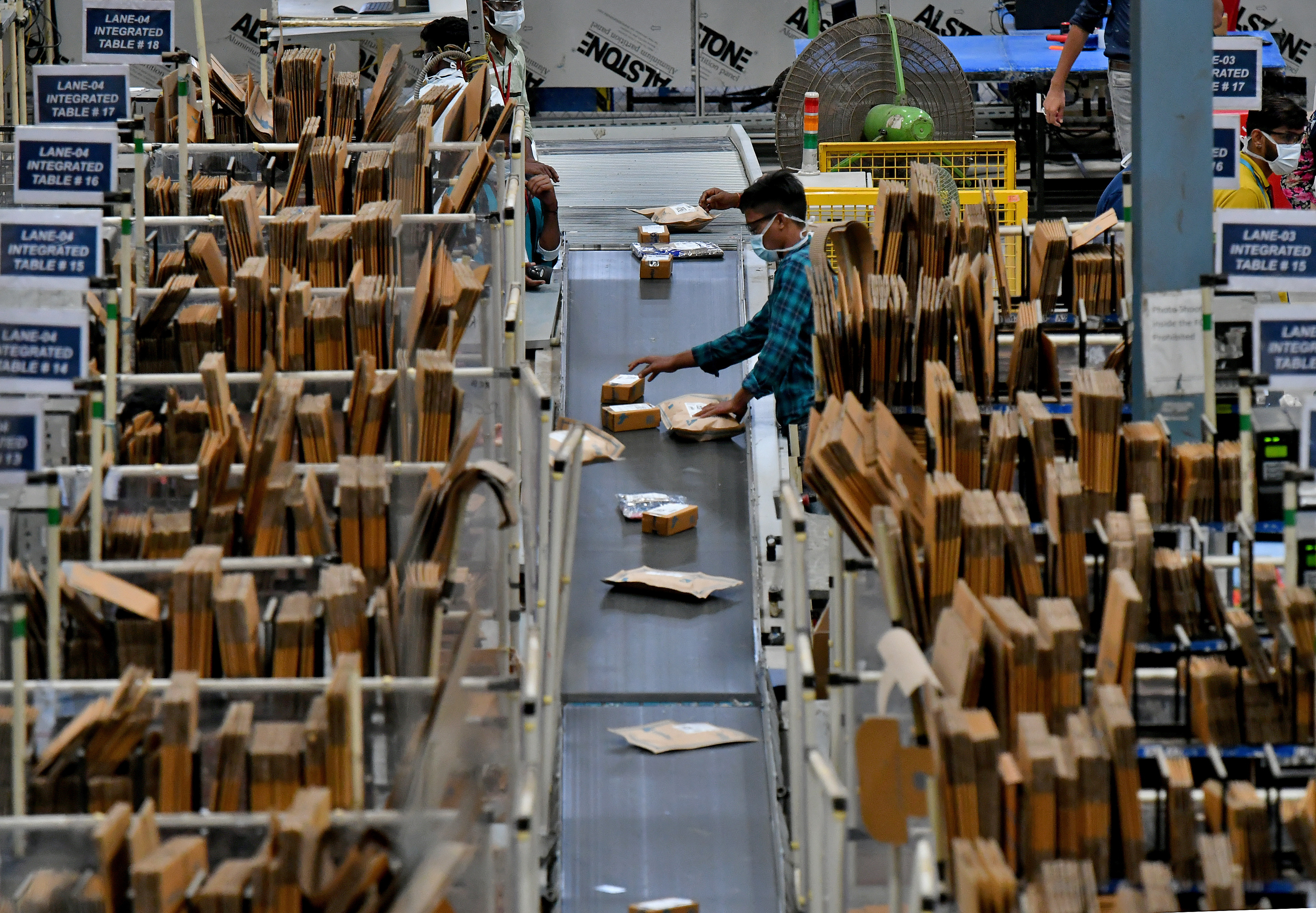 Workers at Flipkart, a leading e-commerce firm in India, sort packets on a conveyor belt inside its fulfilment centre on the outskirts of Bengaluru