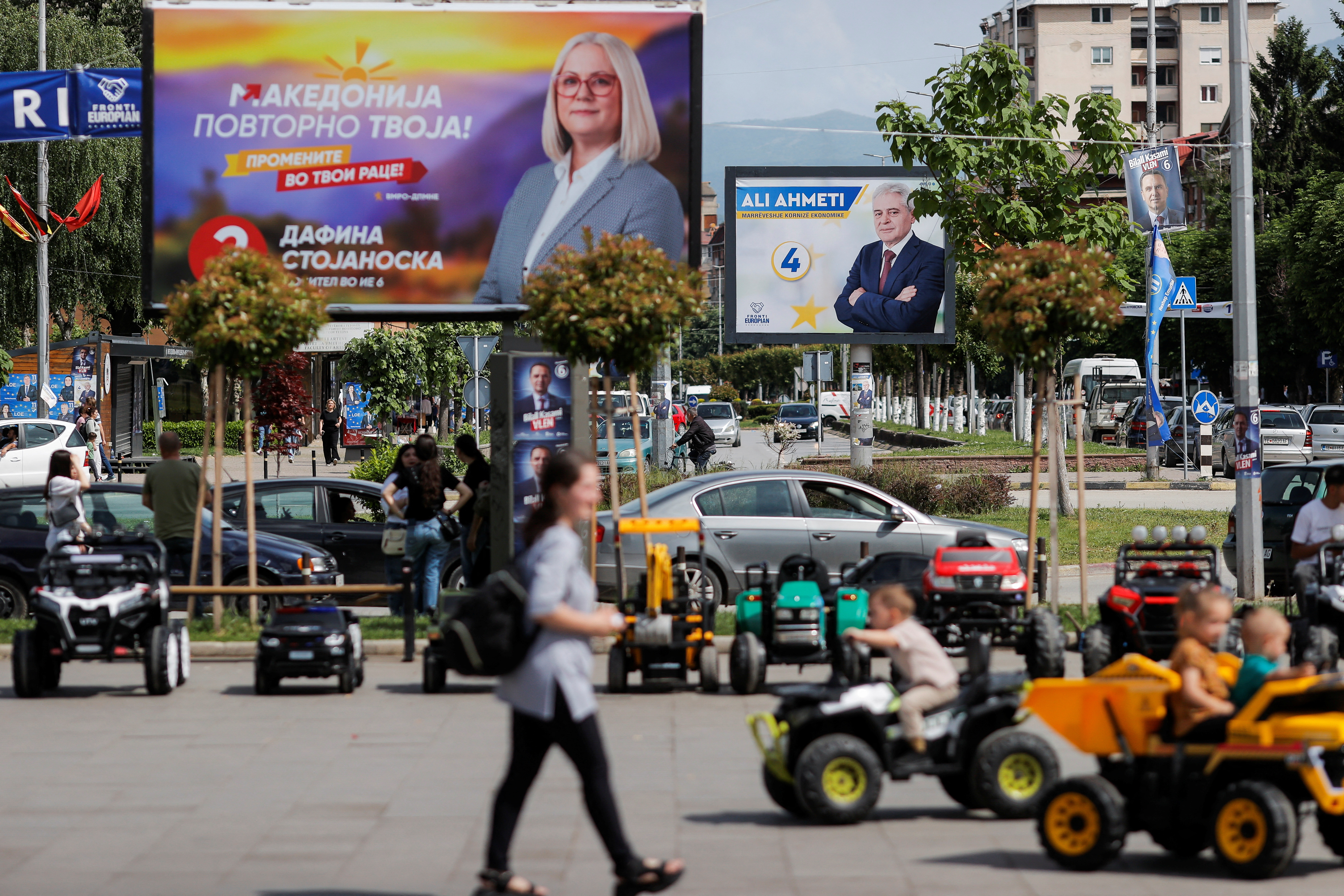 Children play near campaign billboards for the upcoming parliamentary and presidential elections, in Tetovo