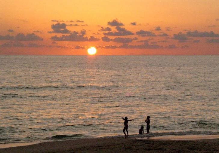 CHILDREN PLAY ON VENICE BEACH AS THE SUN SETS IN FLORIDA.