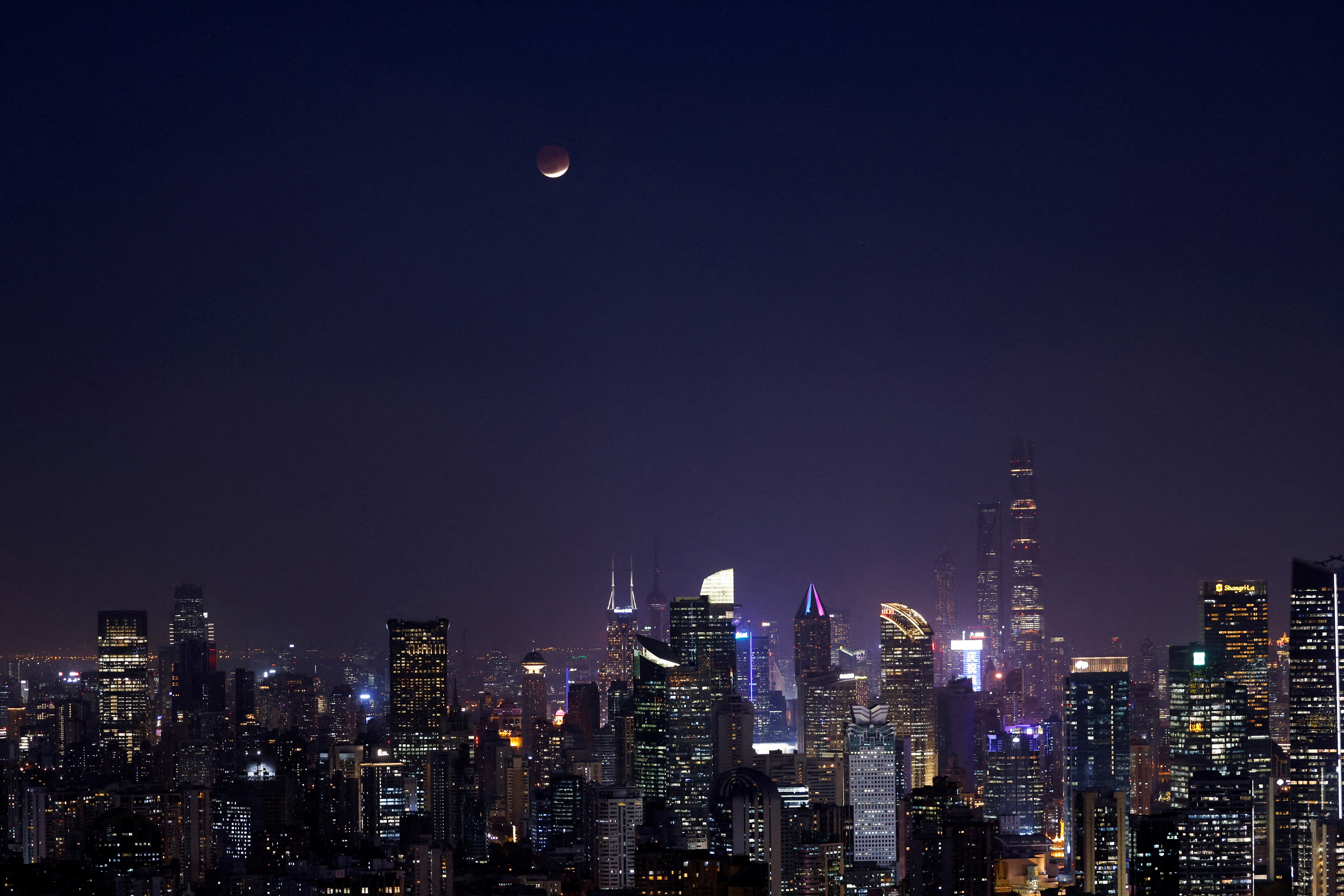Lunar eclipse rises over the skyline of Shanghai