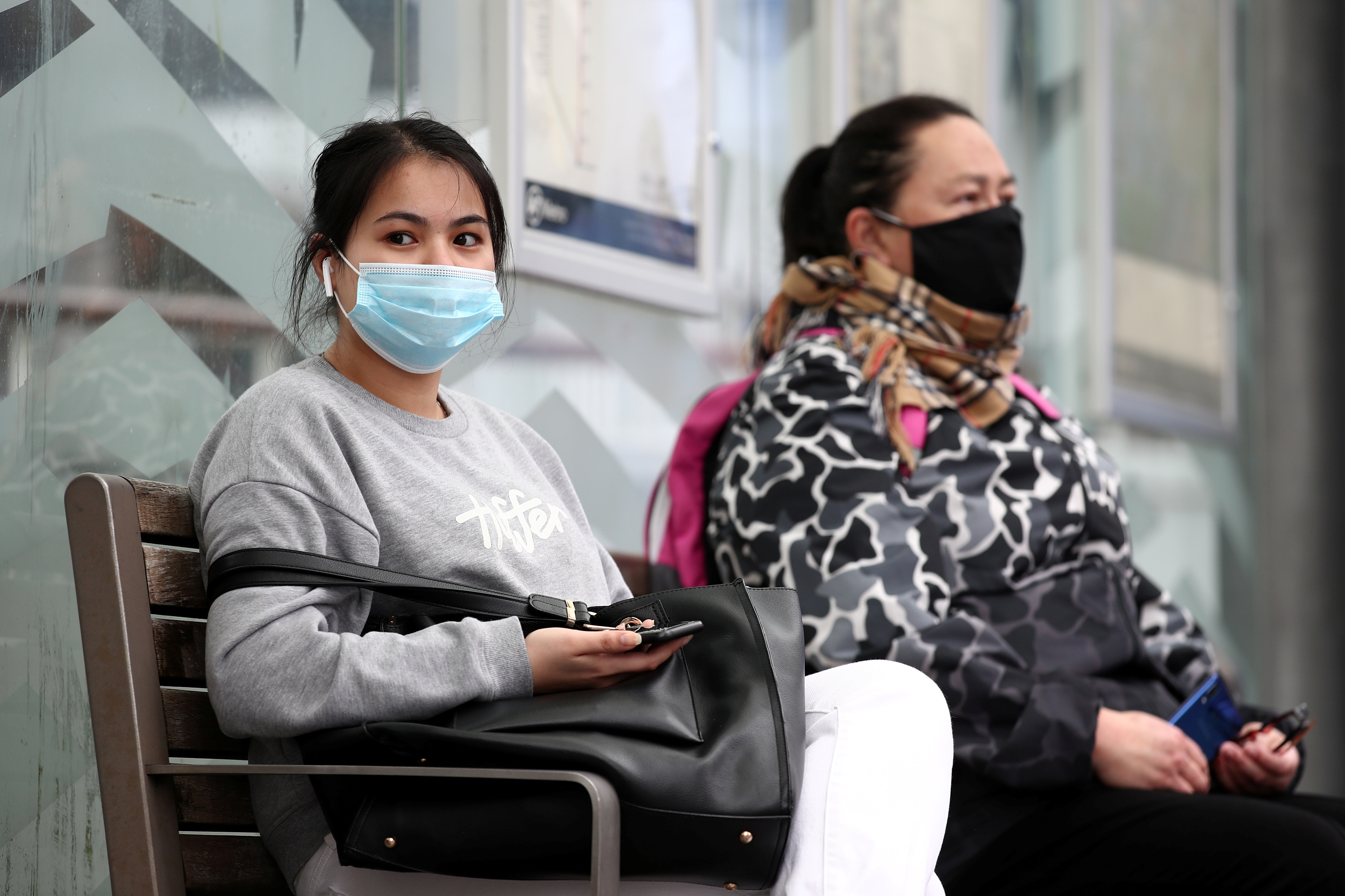 People wearing face masks wait for a bus on the first day of New Zealand's new coronavirus disease (COVID-19) safety measure that mandates wearing of a mask on public transport, in Auckland, New Zealand, August 31, 2020.  REUTERS/Fiona Goodall
