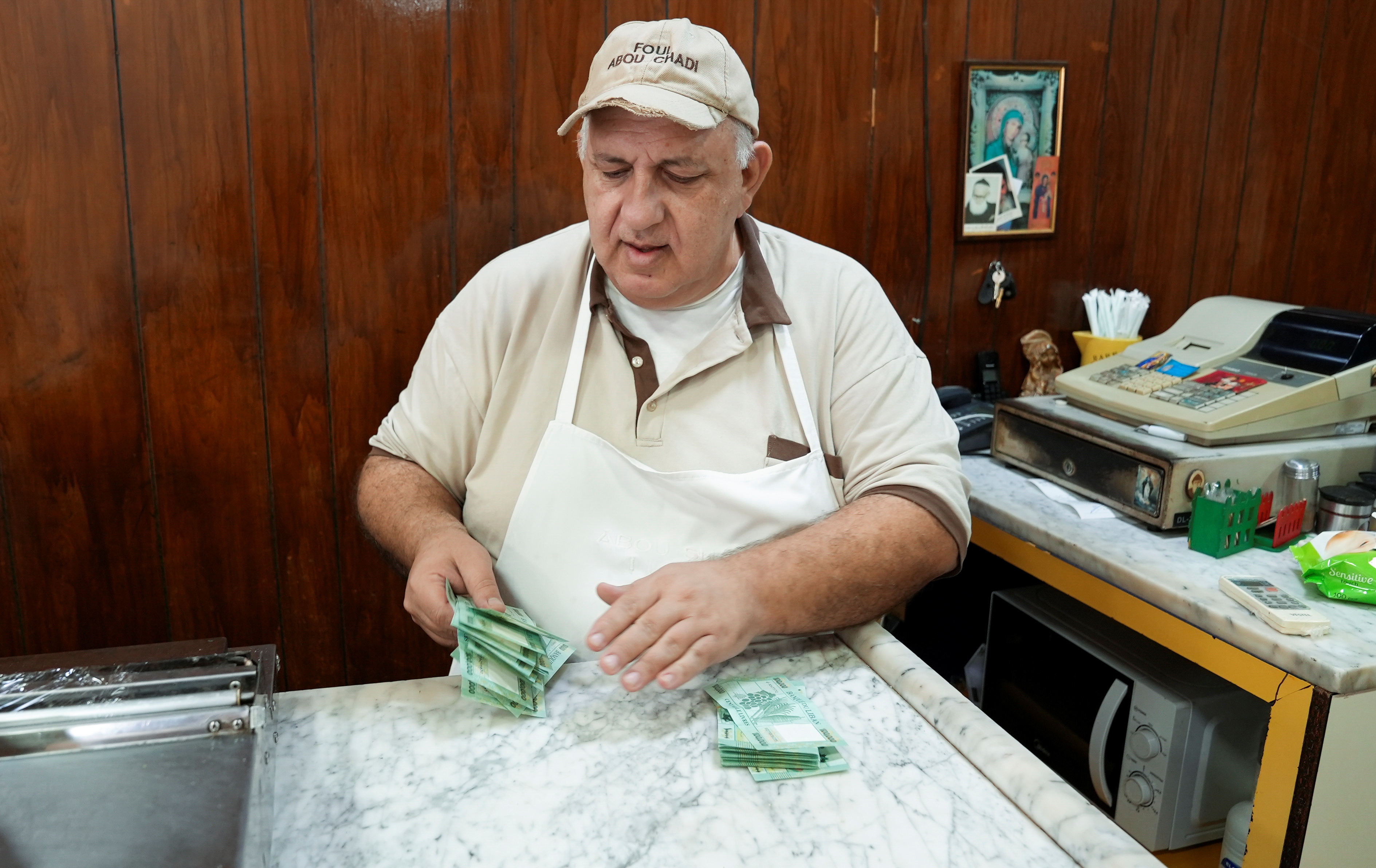 Antoine Haddad, known as Abou Chadi, a Lebanese restaurant owner, counts Lebanese pounds in Jal el-Dib