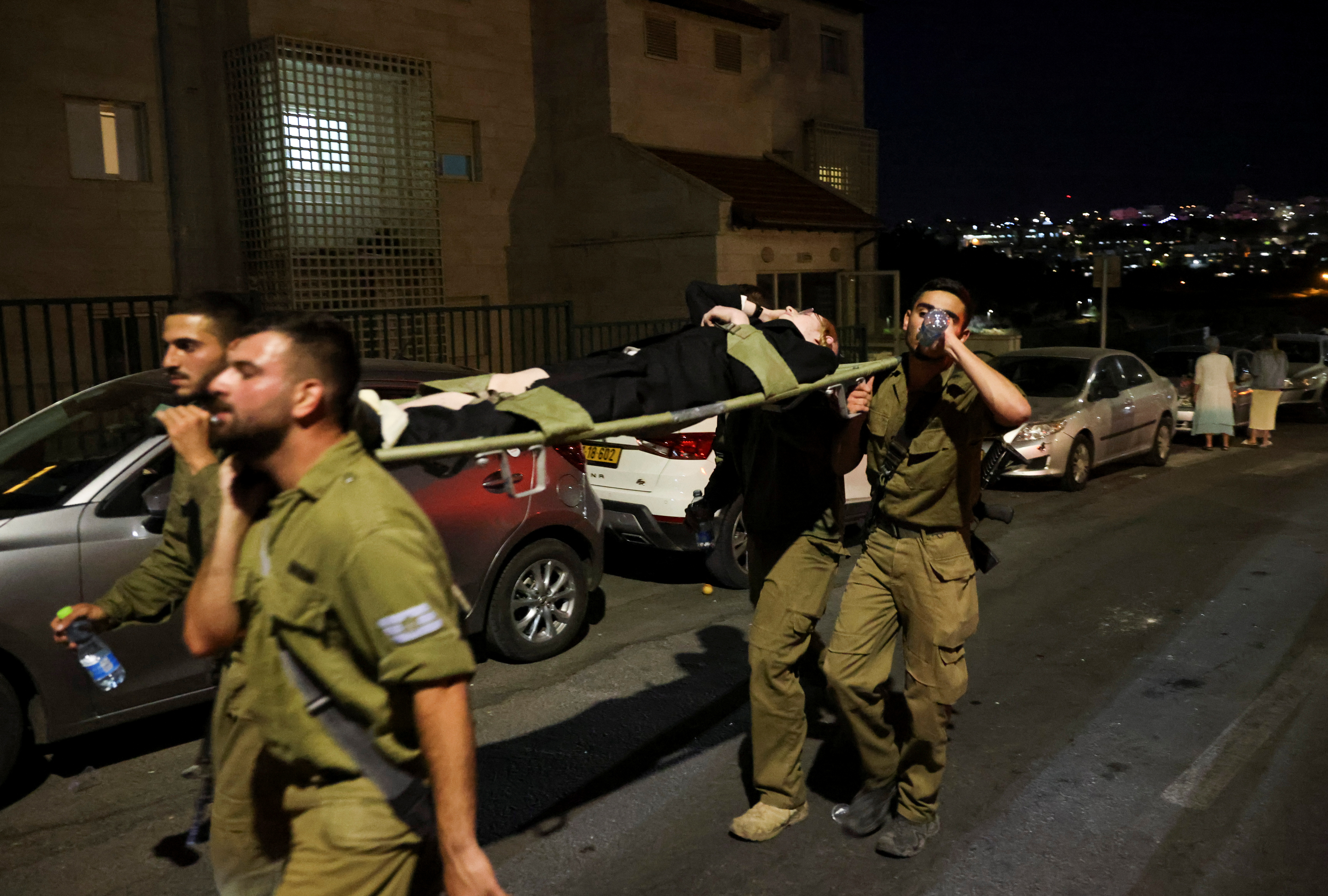 Members of the military carry an injured man outside a synagogue where a grandstand collapsed during a religious celebration in Givat Zeev, in the occupied West Bank, May 16, 2021. REUTERS/Ronen Zvulun