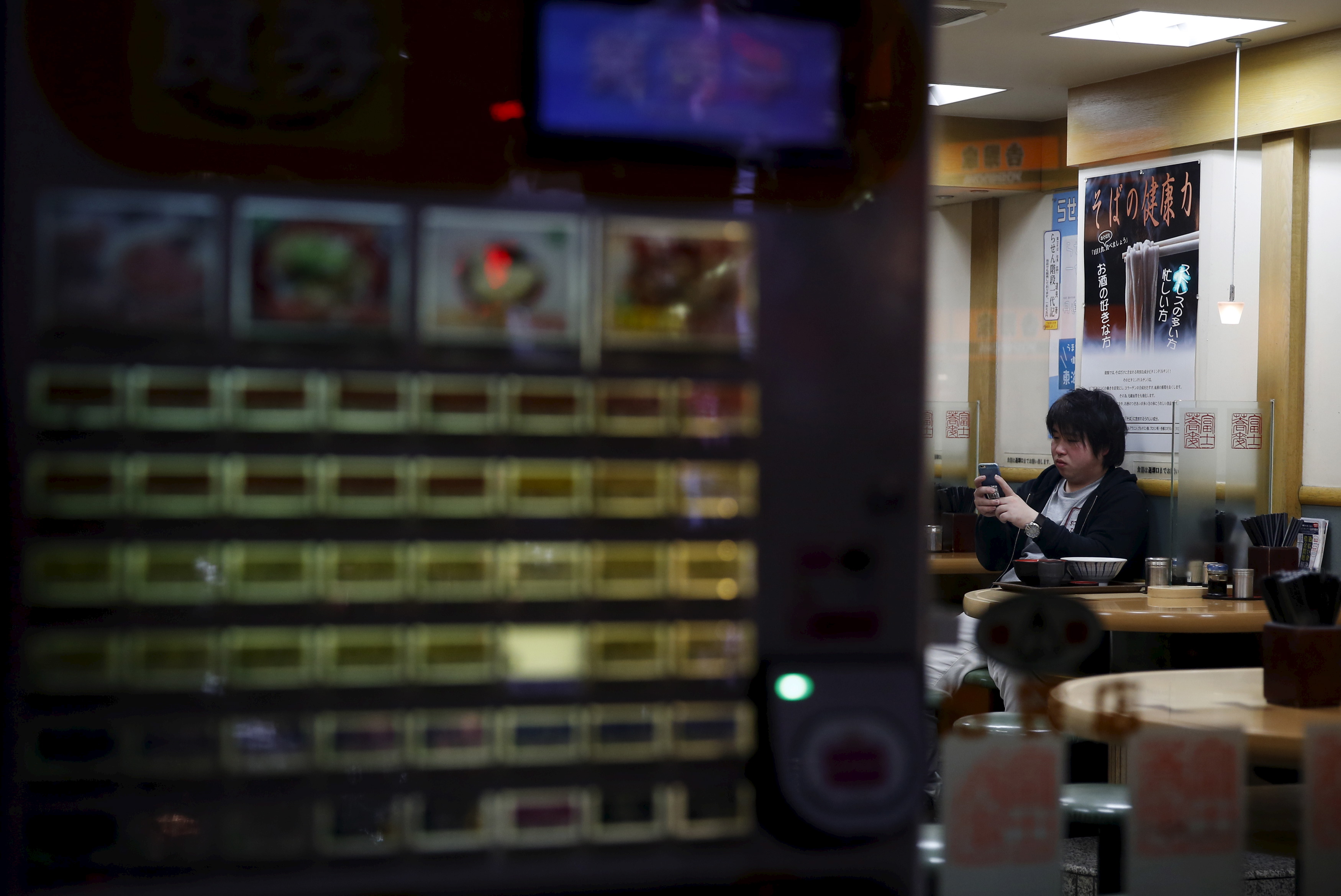 A customer looks at his mobile phone at Soba noodle restaurant at a shopping district in Tokyo