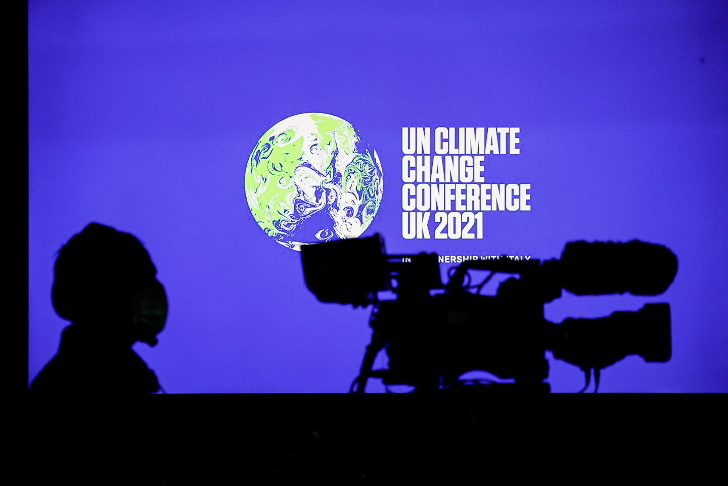 A cameraman sits in front of a screen displaying COP26 logo during a news conference at the UN Climate Change Conference (COP26), in Glasgow, Scotland, Britain, November 5, 2021. REUTERS/Phil Noble