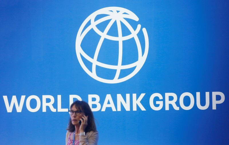 A participant stands near a logo of World Bank at the International Monetary Fund - World Bank Annual Meeting 2018 in Nusa Dua