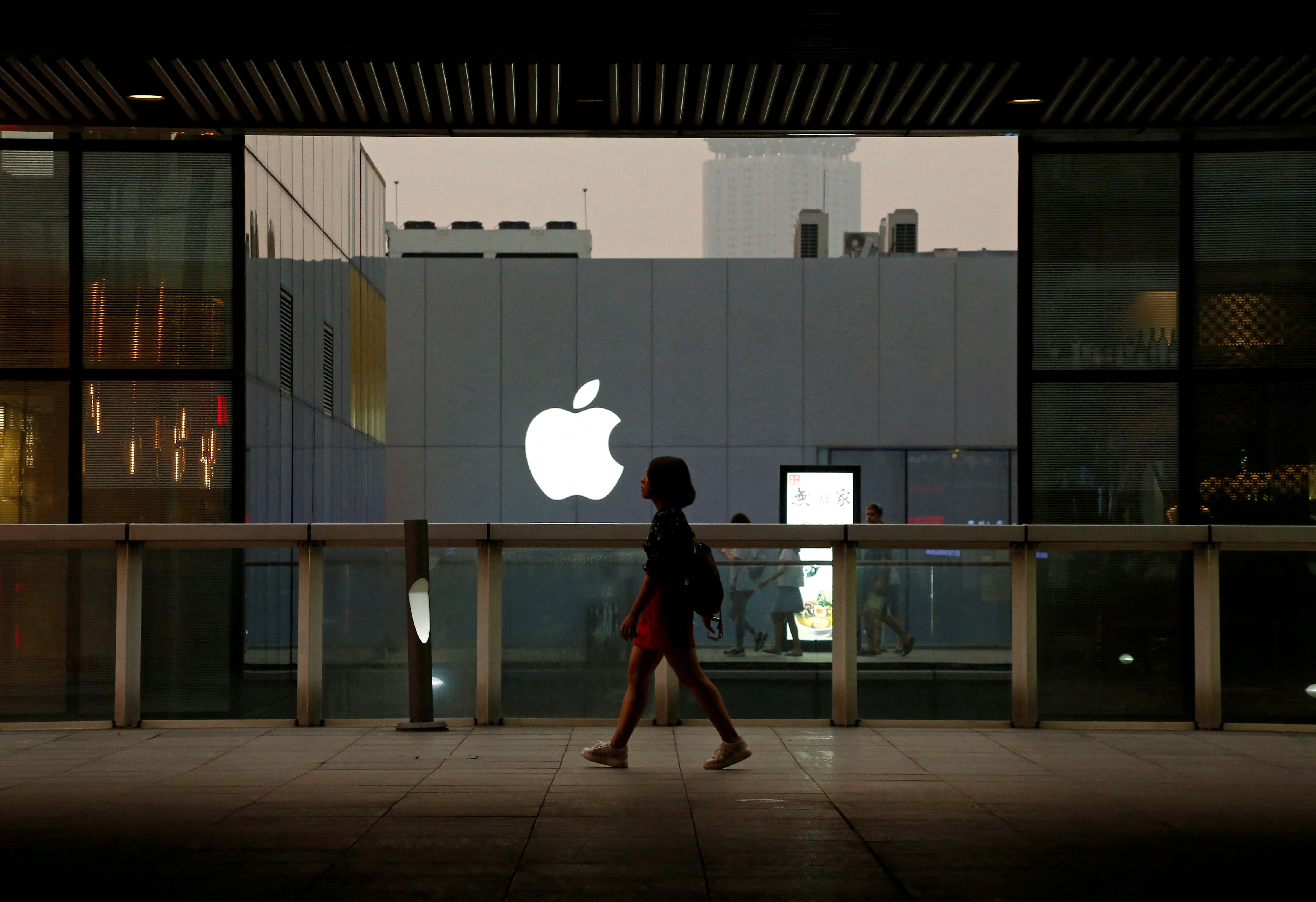 A woman walks past an Apple store in Beijing