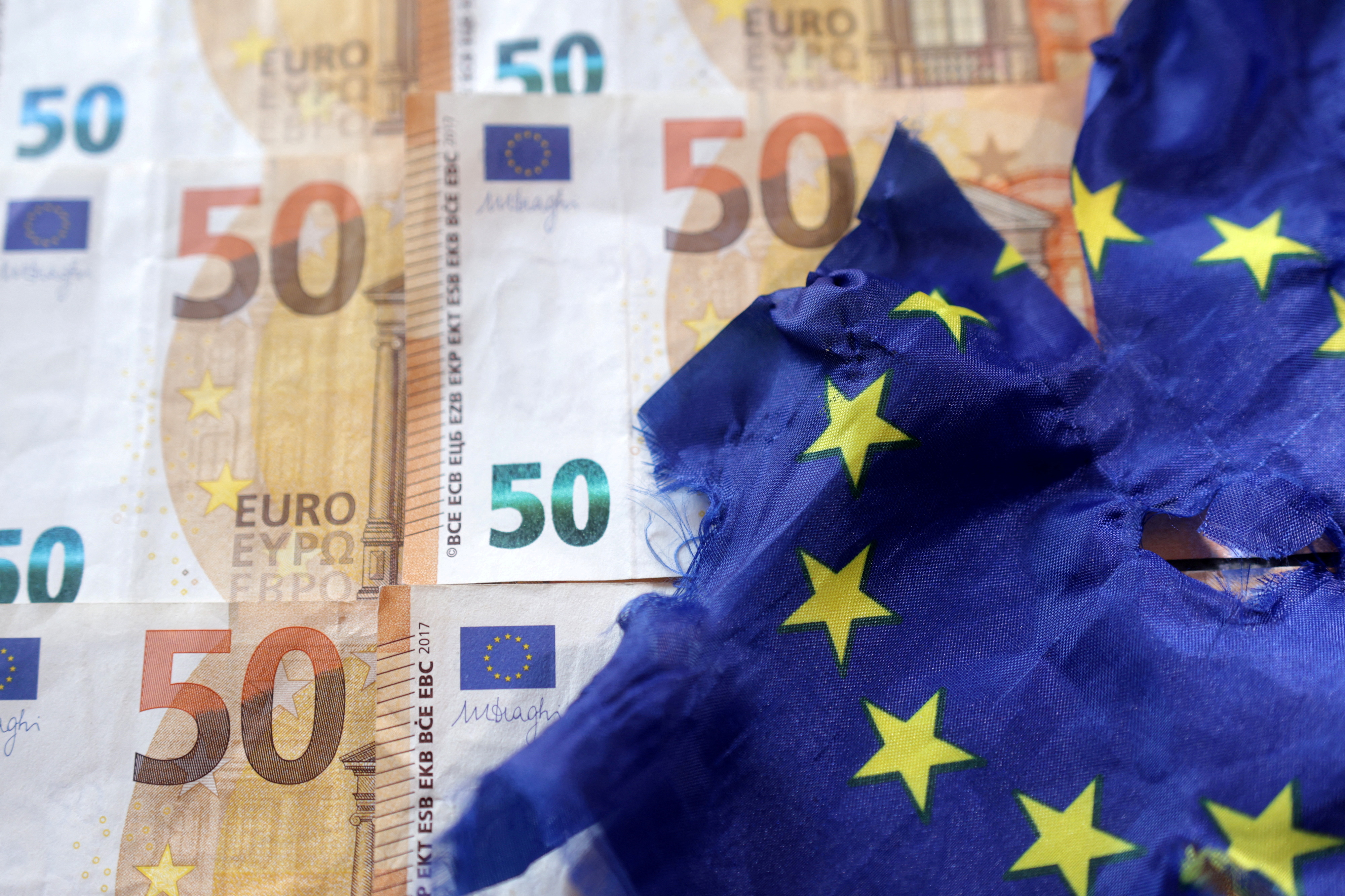 Illustration shows Euro banknotes and torn EU flag