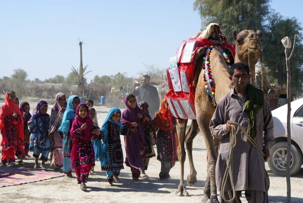 Children react as a camel carries books, in Mand