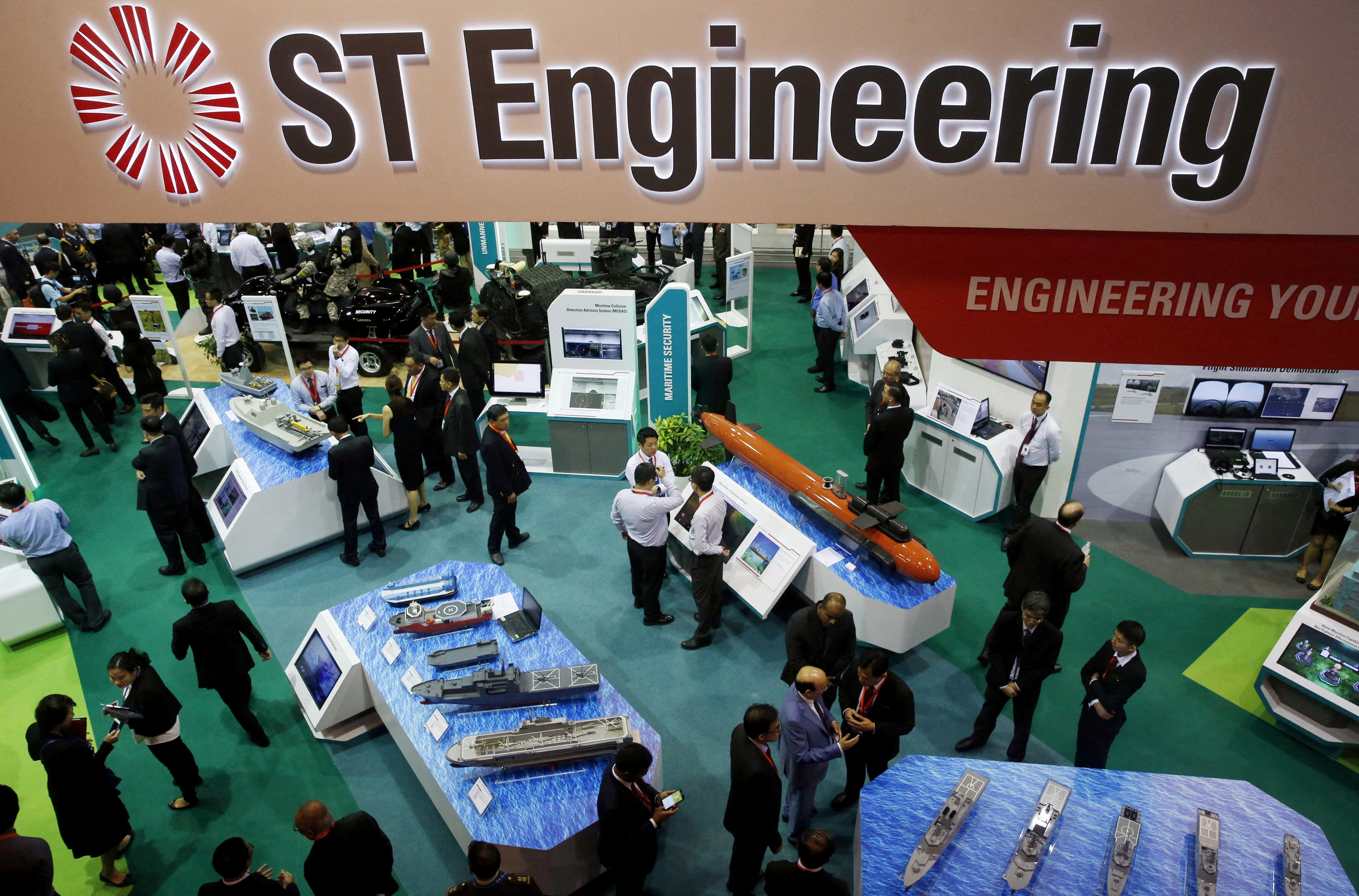 FILE PHOTO: Visitors look at displays at the Singapore Technology (ST) Engineering booth during the opening day of the Singapore Airshow at Changi Exhibition Center