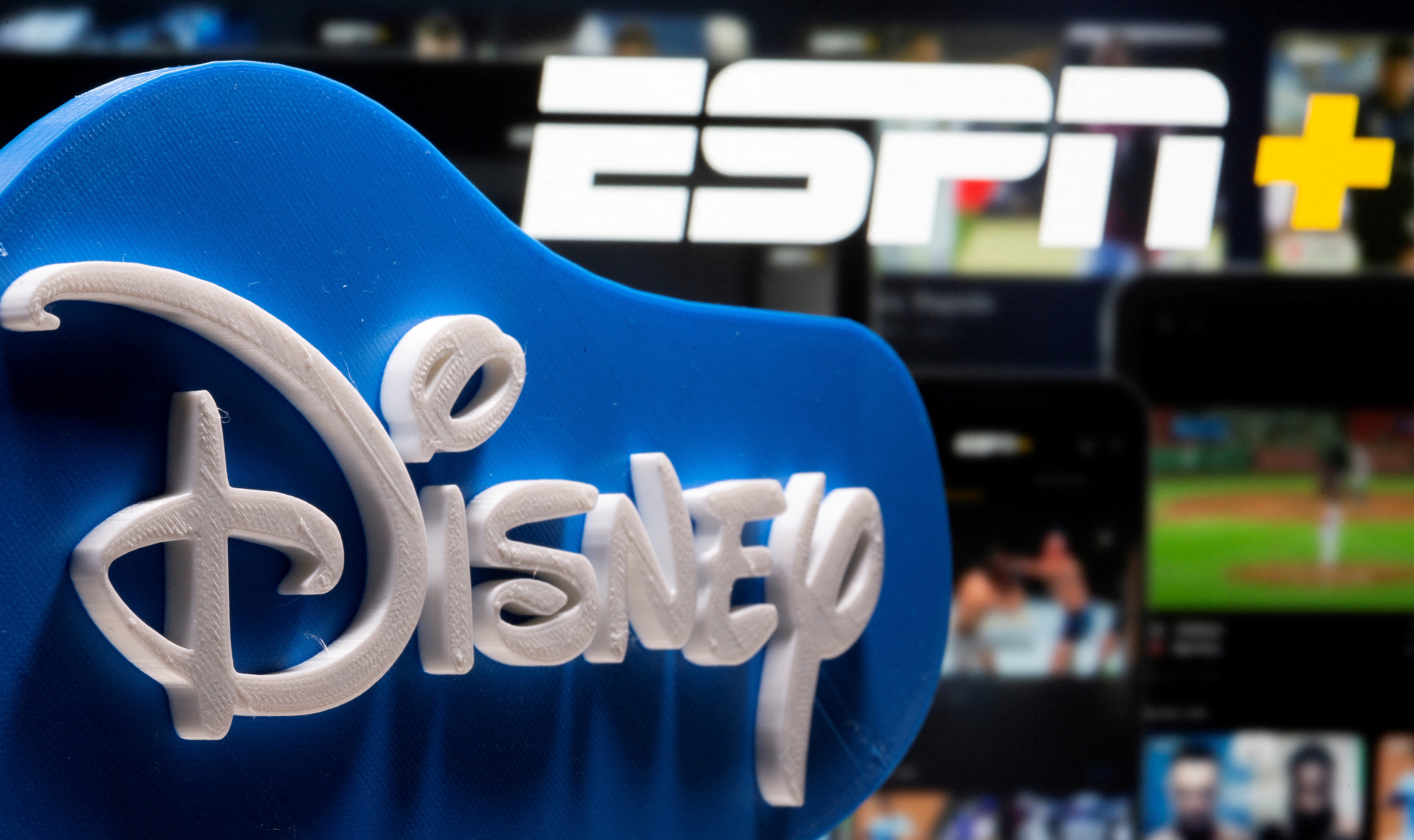 Photo illustration of a 3D printed Disney logo seen in front of the ESPN+ logo