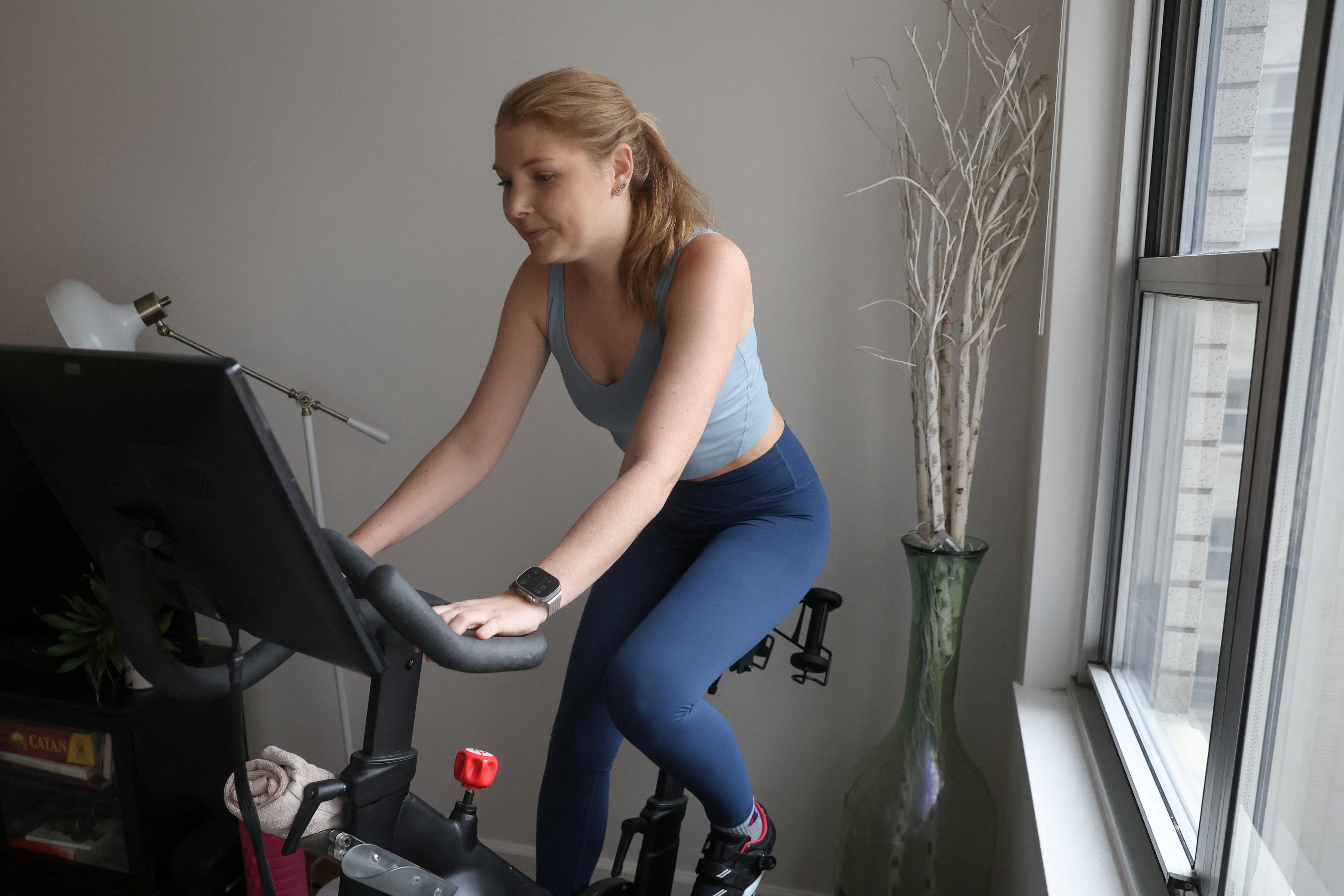 Lauren Maginness rides an exercise bike wearing Dupes, short for duplicate, at her apartment in New York City