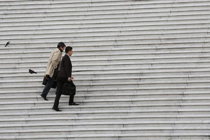 Businessmen carry briefcases as they climb the stairs under the Arche de la Defense in the financial and business district west of Paris