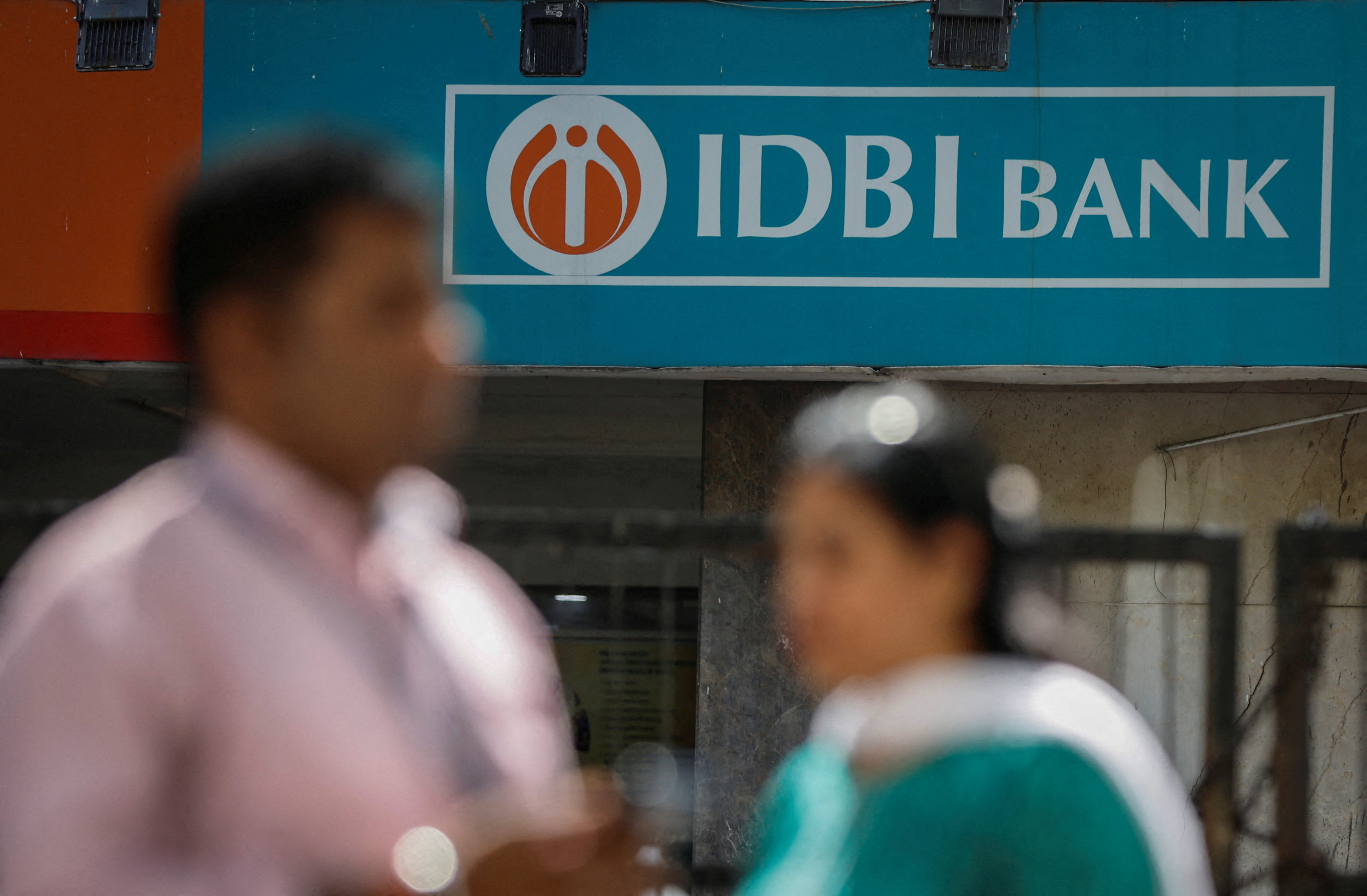 People walk past a branch of IDBI Bank in New Delhi