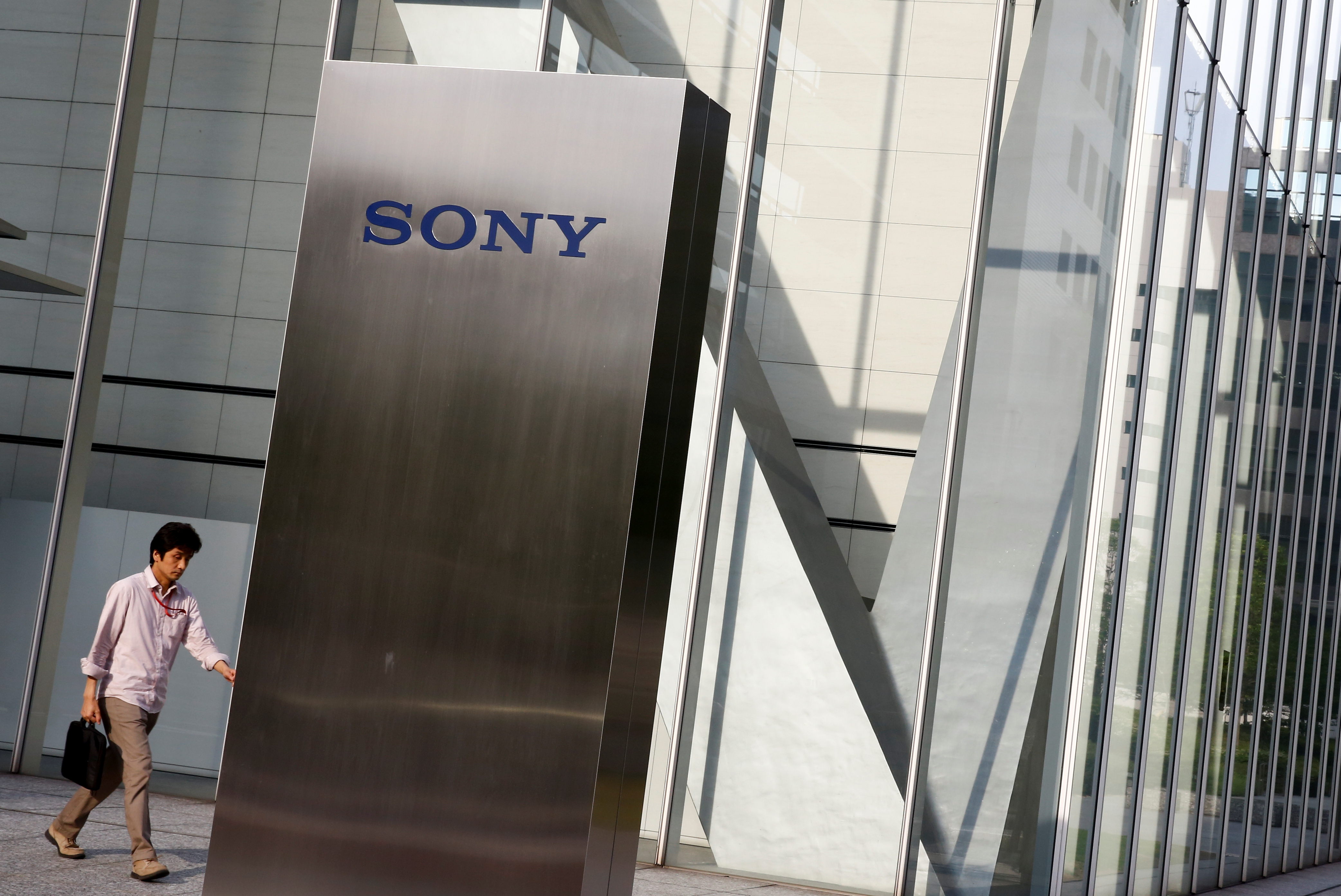 A man walks past the Sony brand logo outside the headquarters of Sony Corp in Tokyo