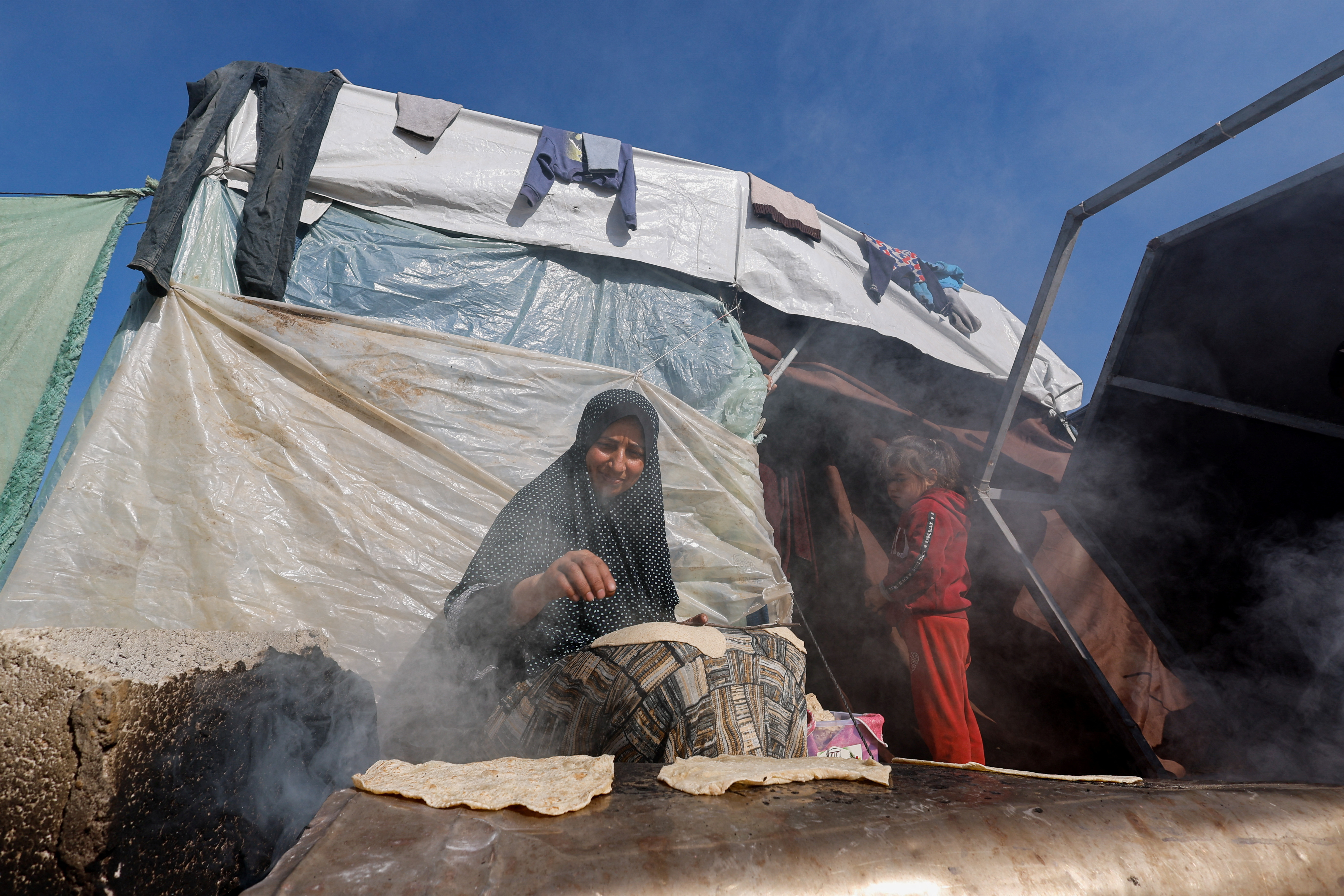 Displaced Palestinians, who fled their houses due to Israeli strikes, shelter in a tent camp near the border with Egypt, in Rafah