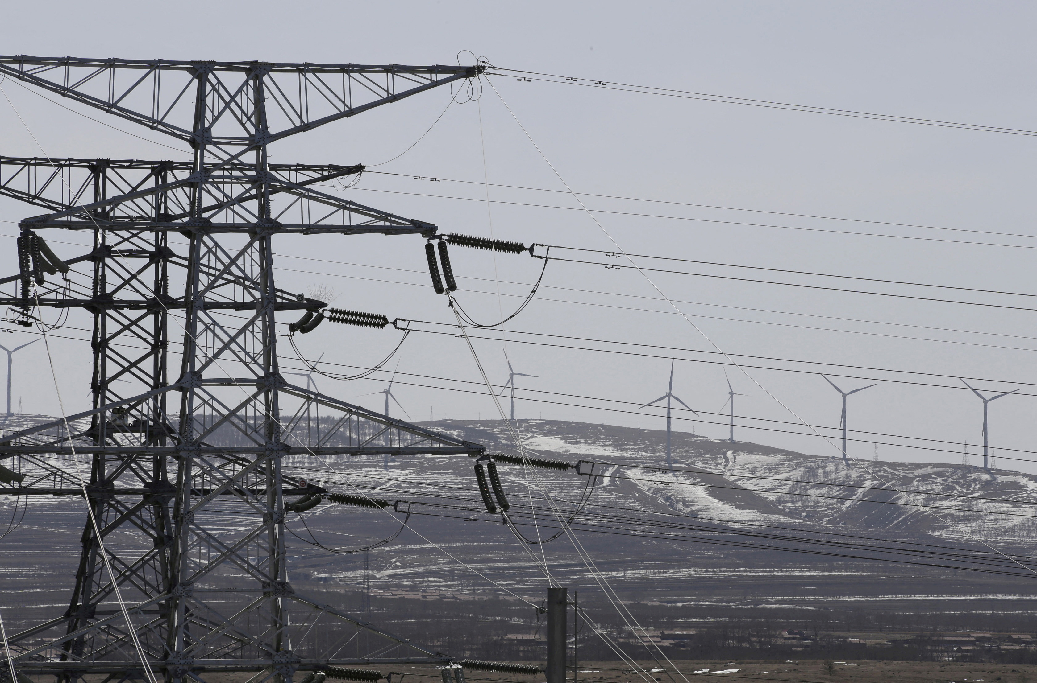 Power lines and wind turbines are pictured at a wind and solar energy storage and transmission power station in Zhangjiakou