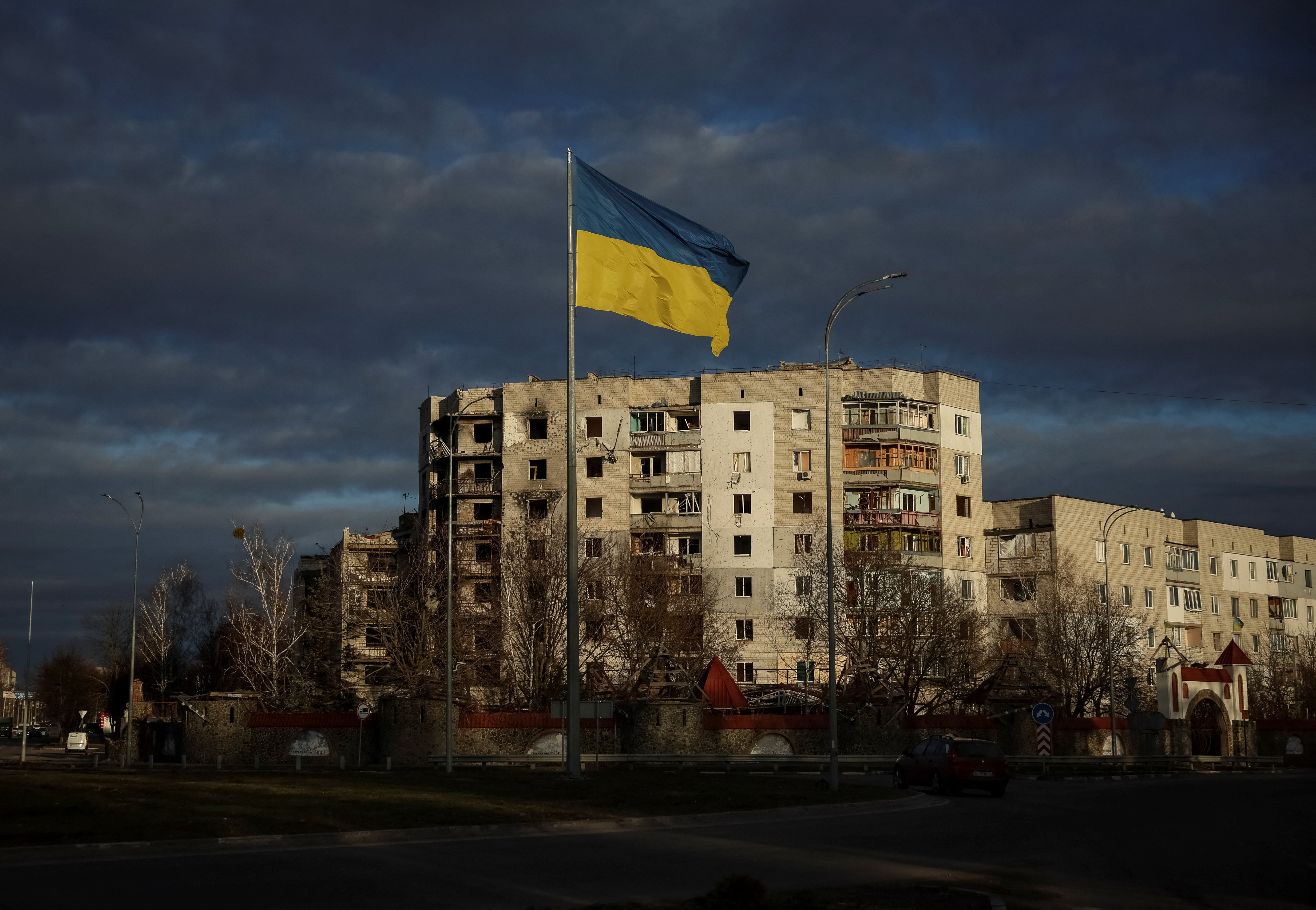 Ukrainian national flag flies near buildings destroyed by Russian military strike in Borodianka