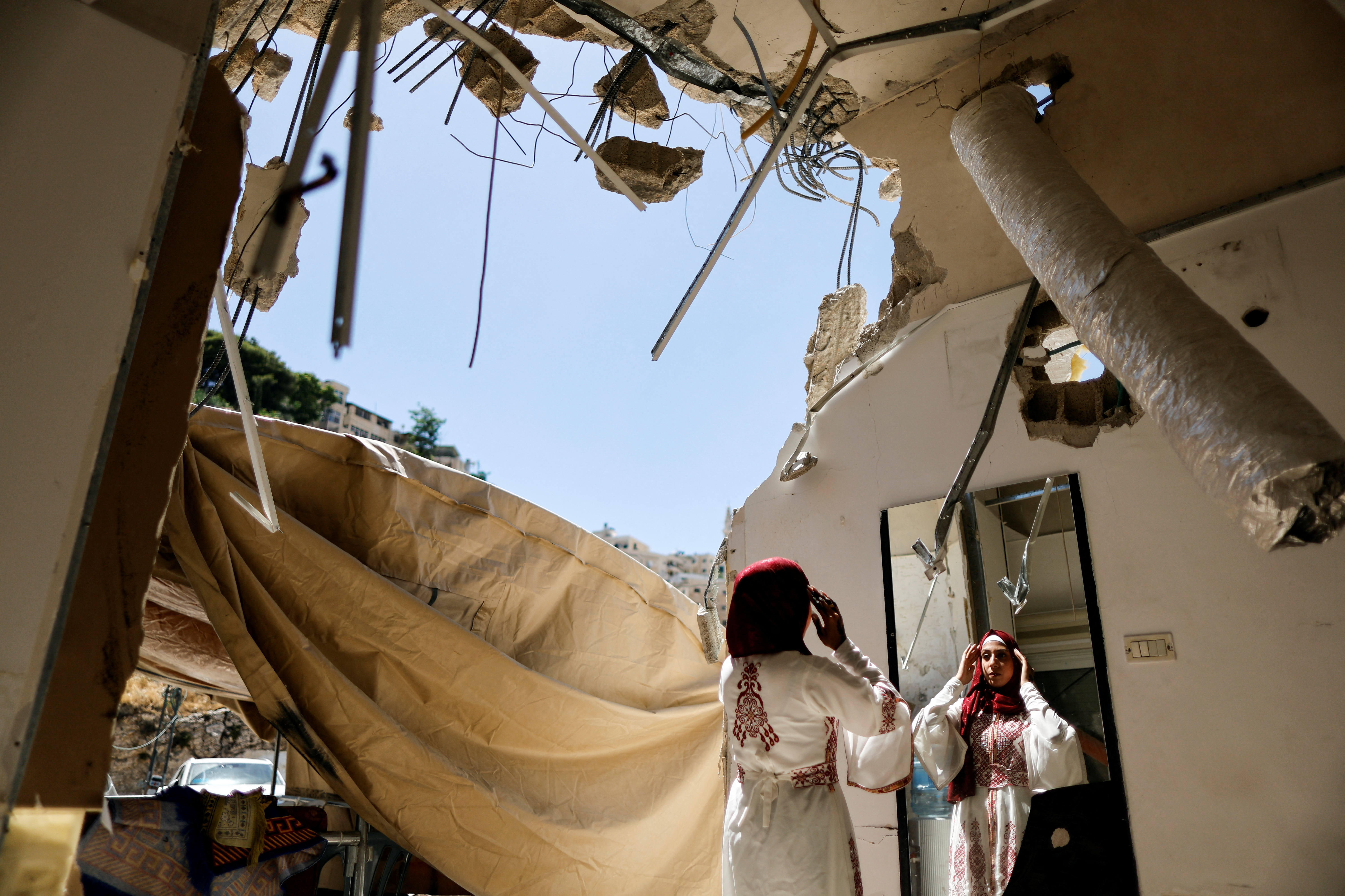 Palestinian bride Rabeha Al-Rajabi looks in the mirror at her house, that was partly demolished by Israeli authority, as part of her pre-wedding ceremony in East Jerusalem