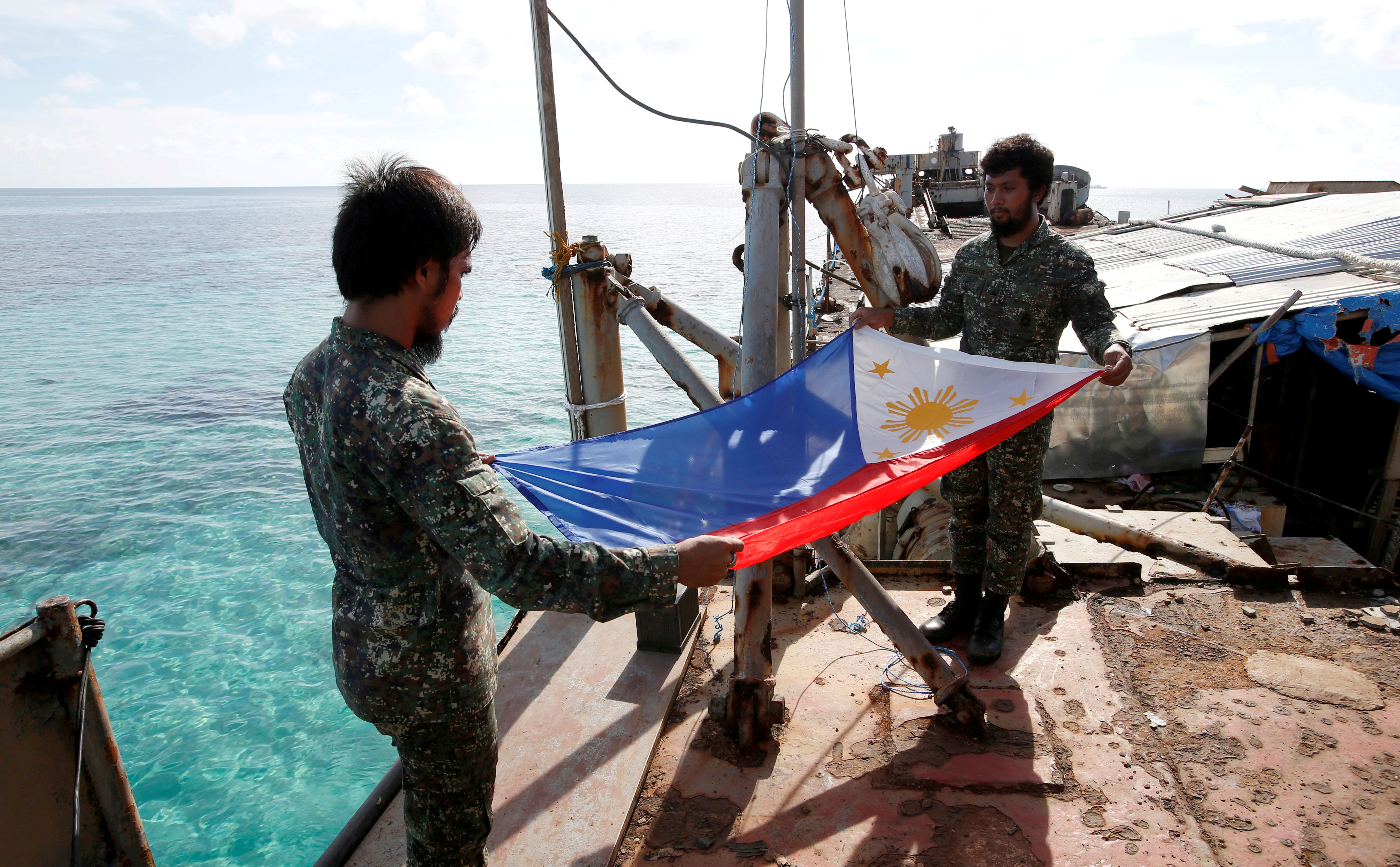 Philippine Marines fold a Philippine national flag during a flag retreat at the BRP Sierra Madre, a marooned transport ship in the disputed Second Thomas Shoal