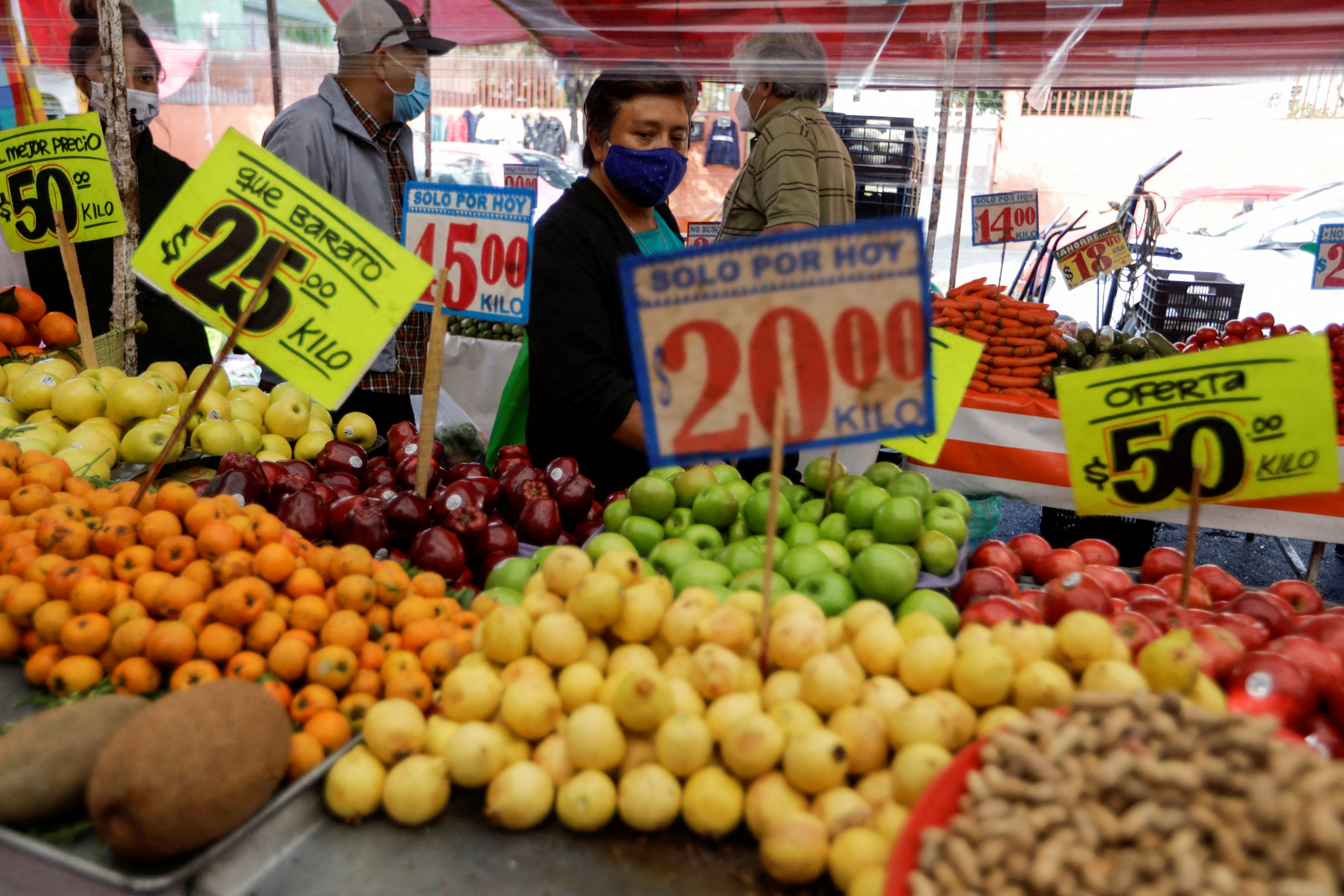 Customers walk past a fruit stall at a street market, in Mexico City