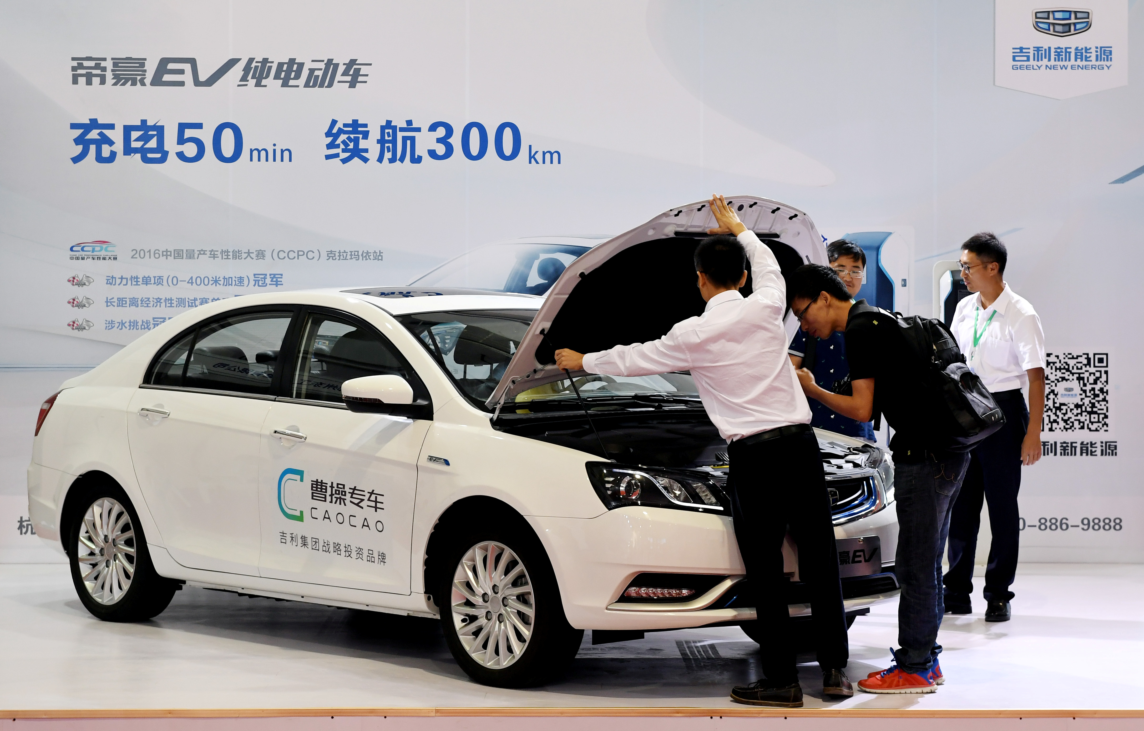 Men look at an electric vehicle of Caocao Zhuanche at a new energy vehicle (NEV) trade fair in Zhengzhou