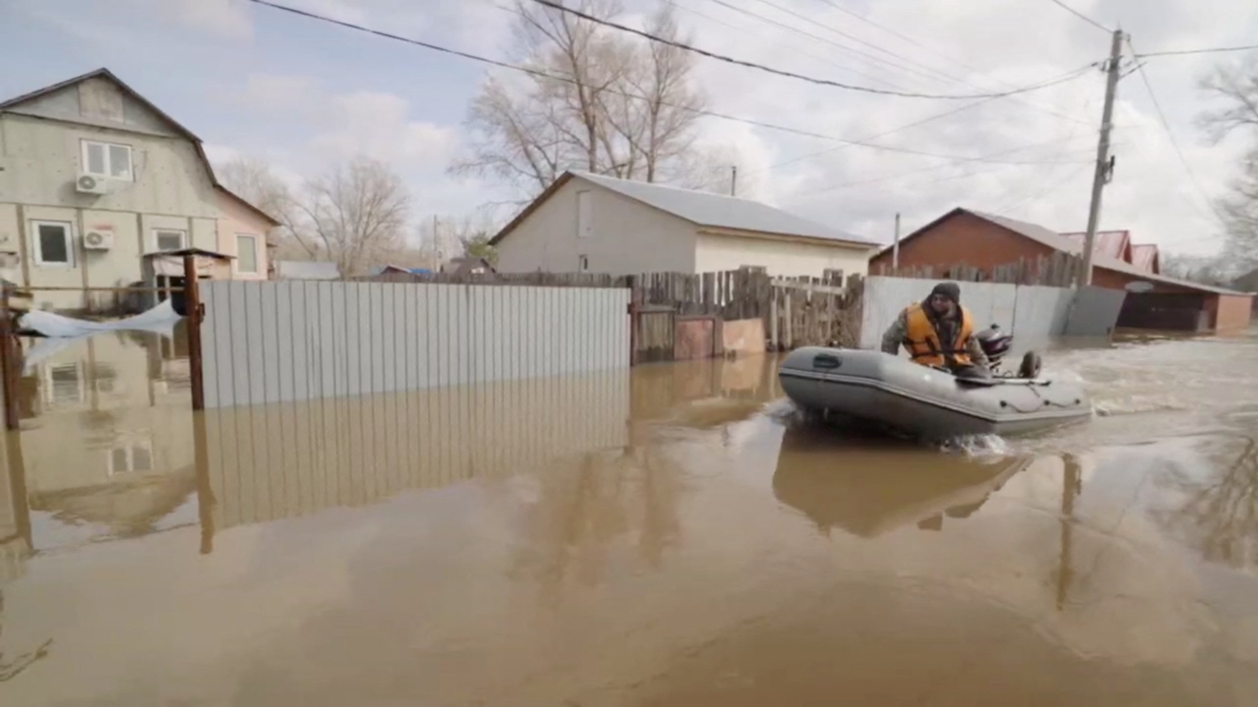 A man rides a boat in a flooded street in Orenburg