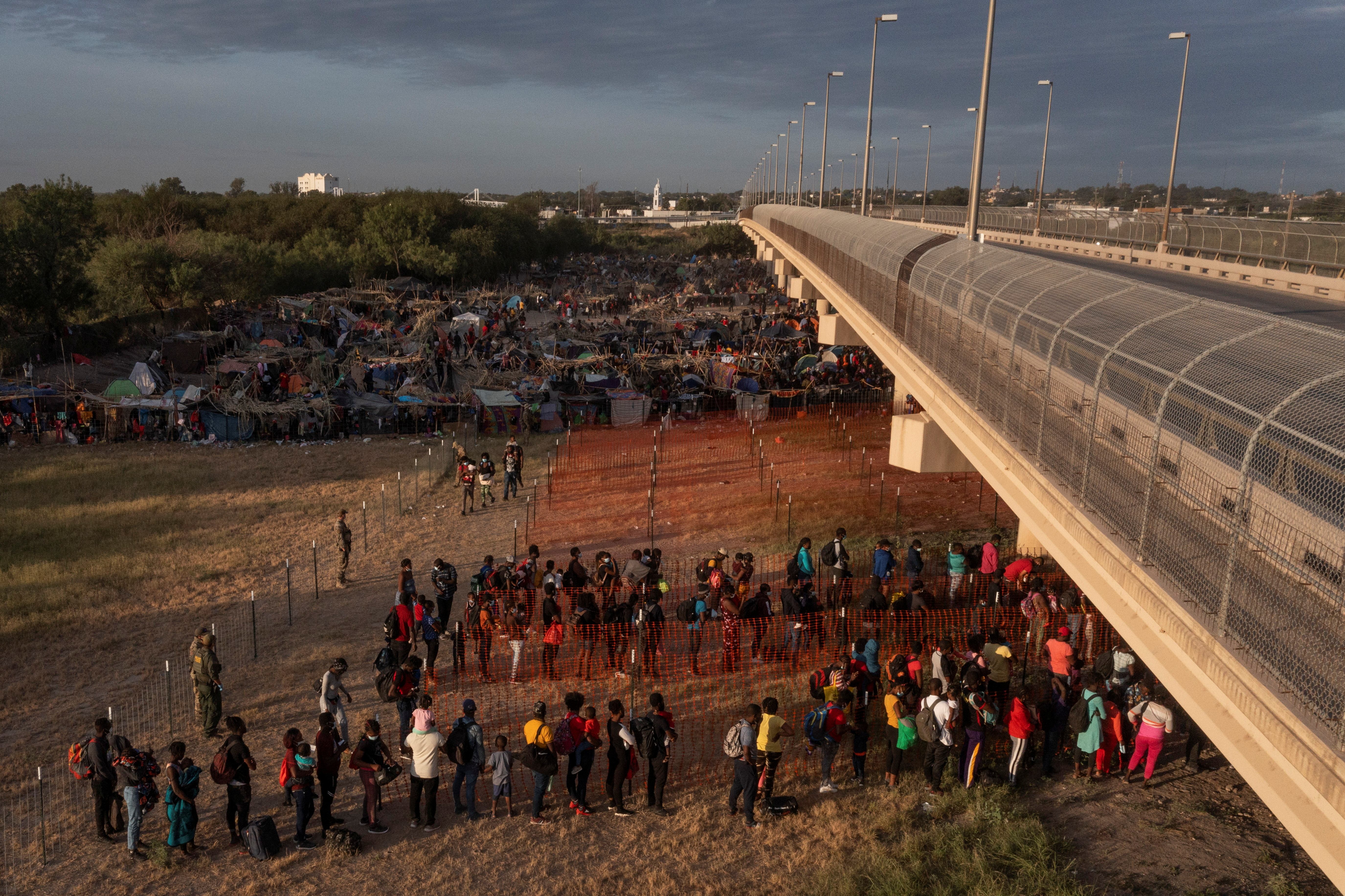 Migrants stand in line while awaiting transport out of a border makeshift camp along the International Bridge in Del Rio, Texas, U.S., September 22, 2021. Picture taken with a drone. REUTERS/Adrees Latif