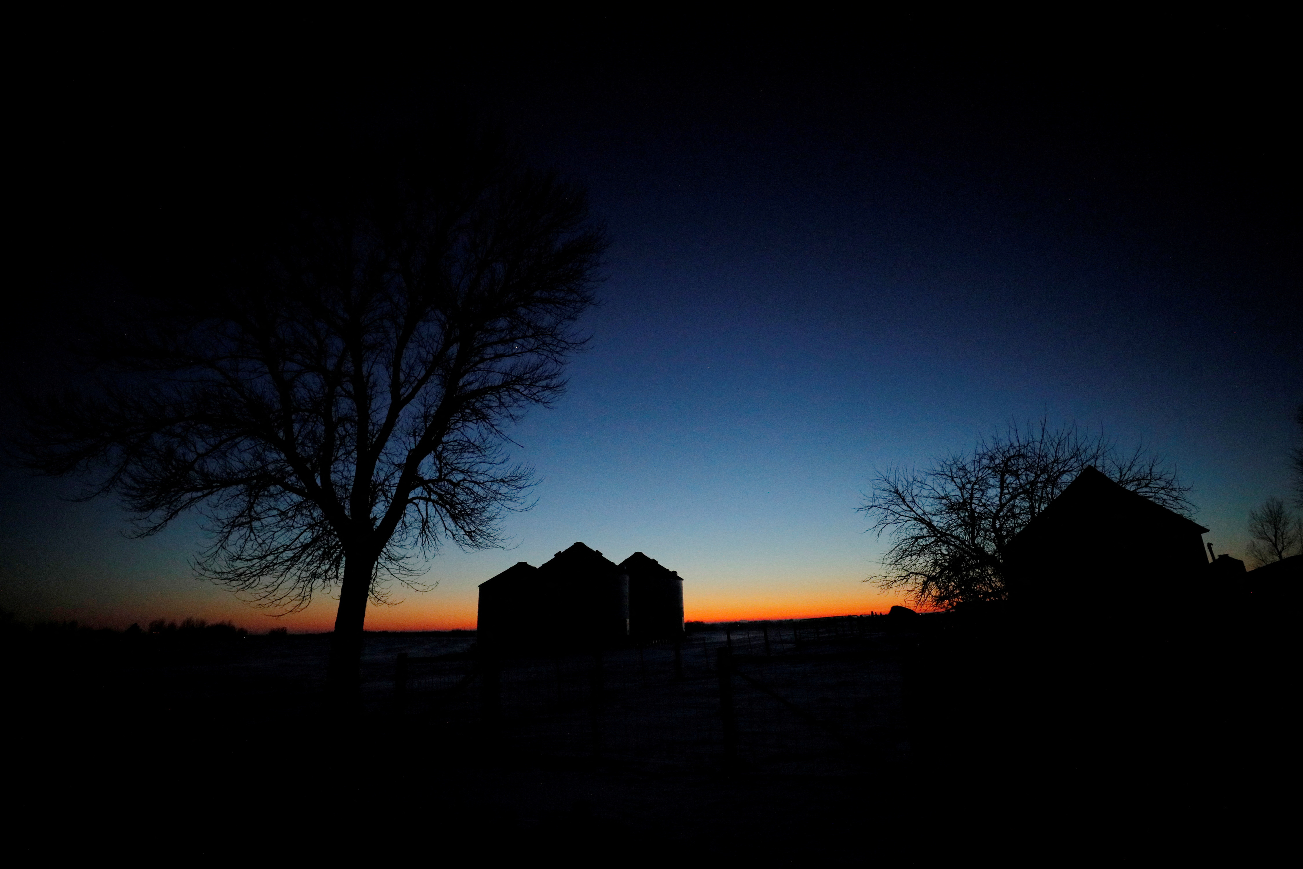 The sun sets behind a farm in Grimes