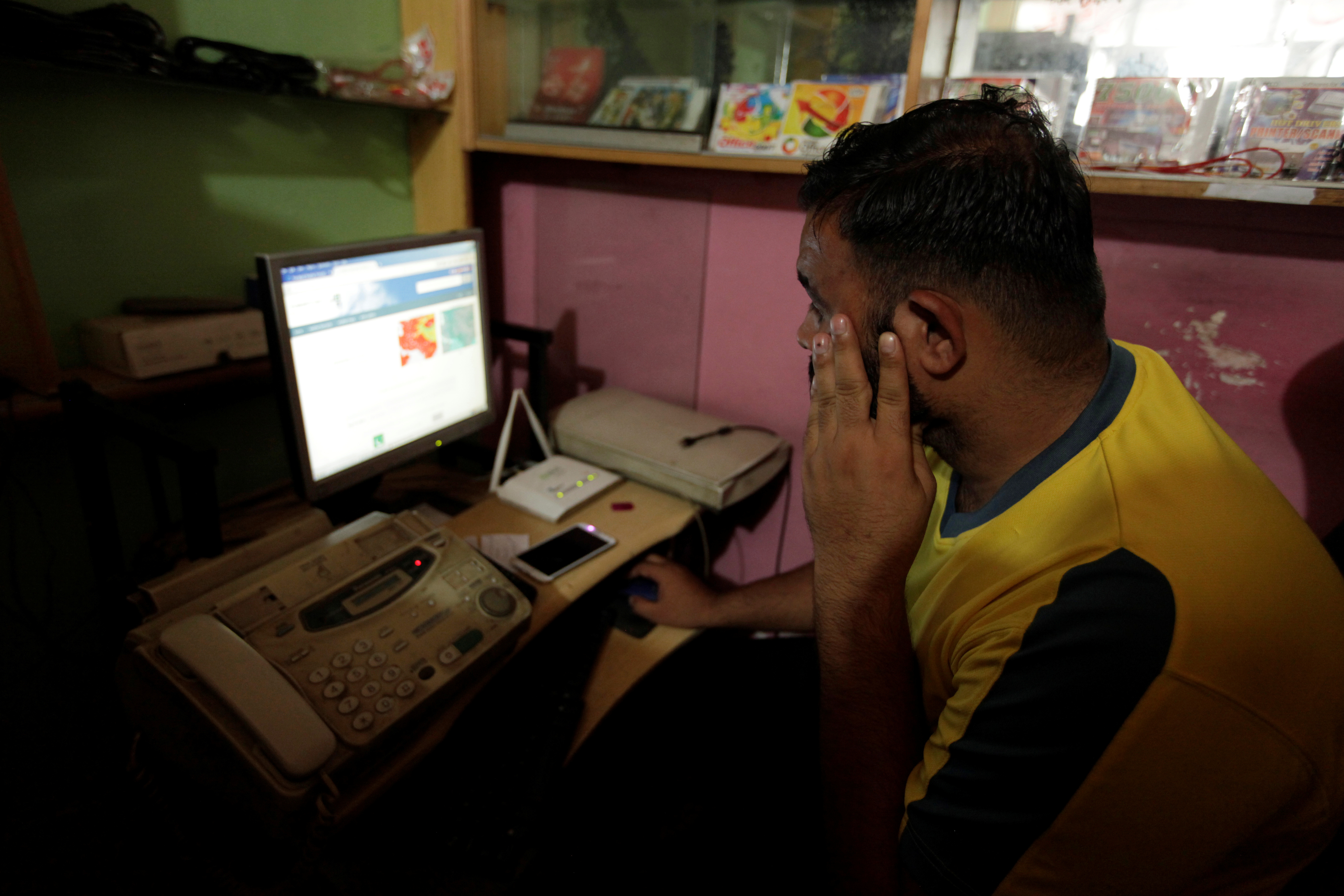 A man explores social media on a computer at an internet club in Islamabad
