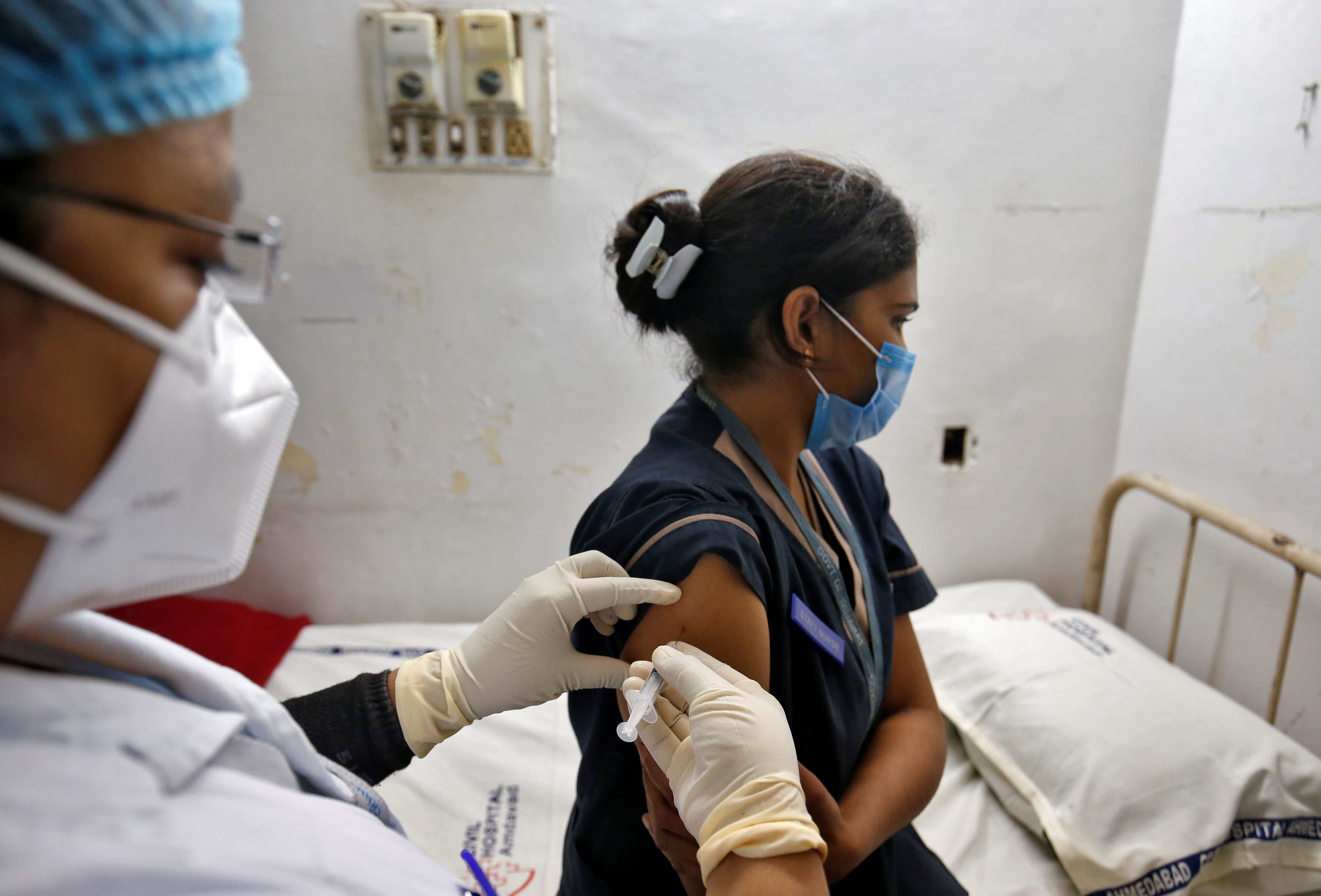 A paramedic administers a vaccine against the coronavirus disease (COVID-19) to a health worker during its trials at Civil Hospital in Ahmedabad