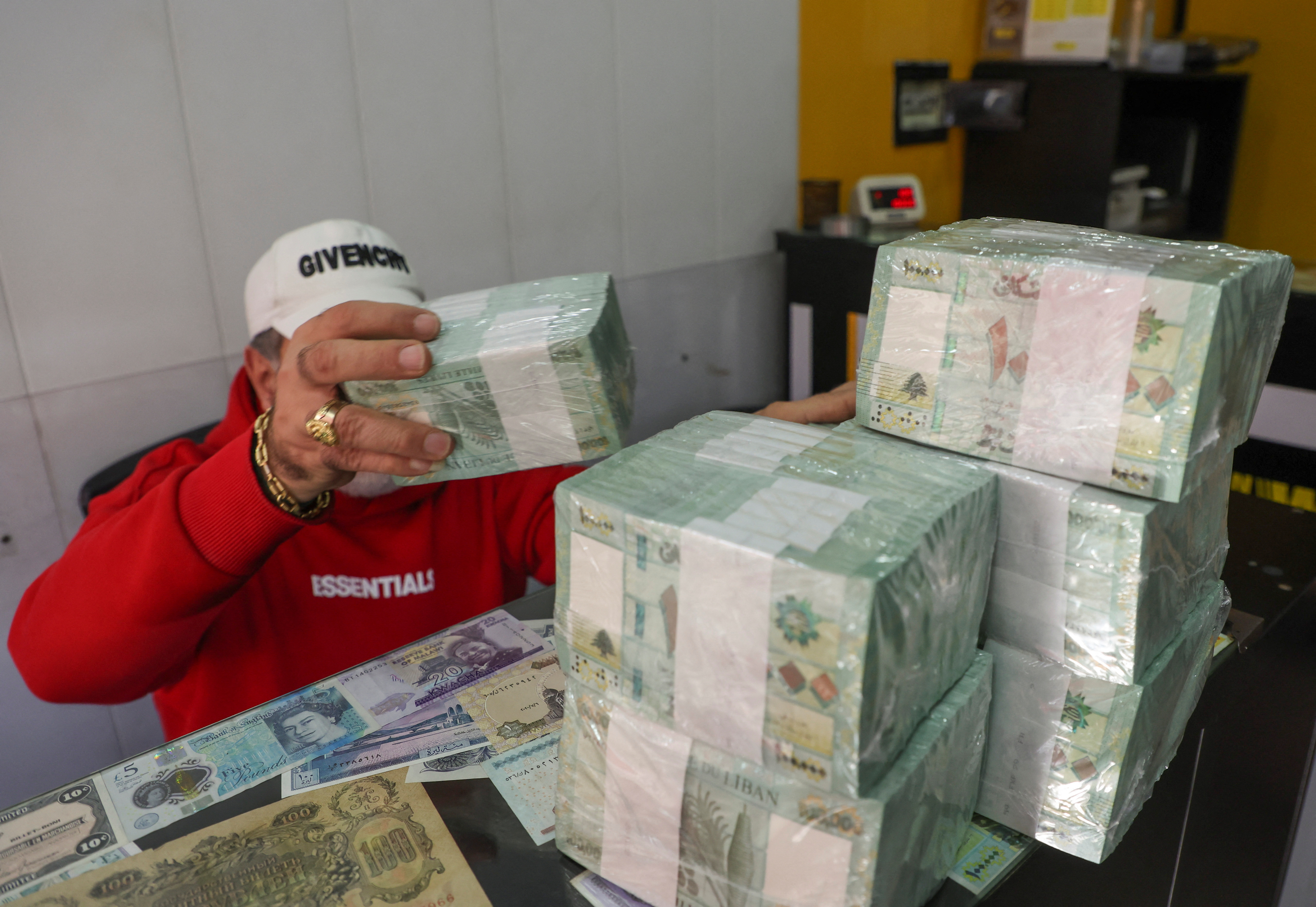 A money exchange vendor holds stacks of Lebanese pound banknotes at a shop in Beirut