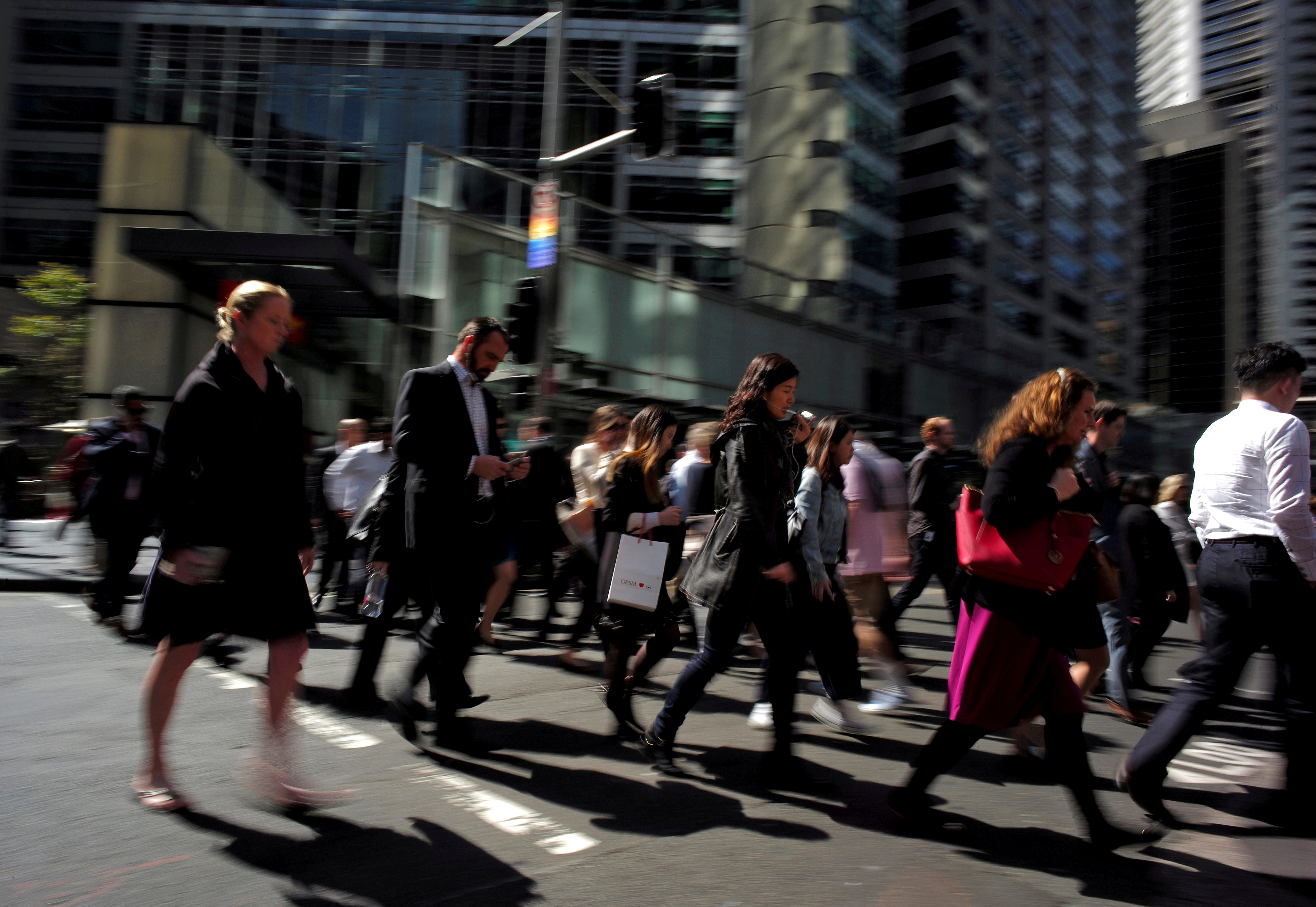 Office workers and shoppers walk through Sydney's central business district in Australia