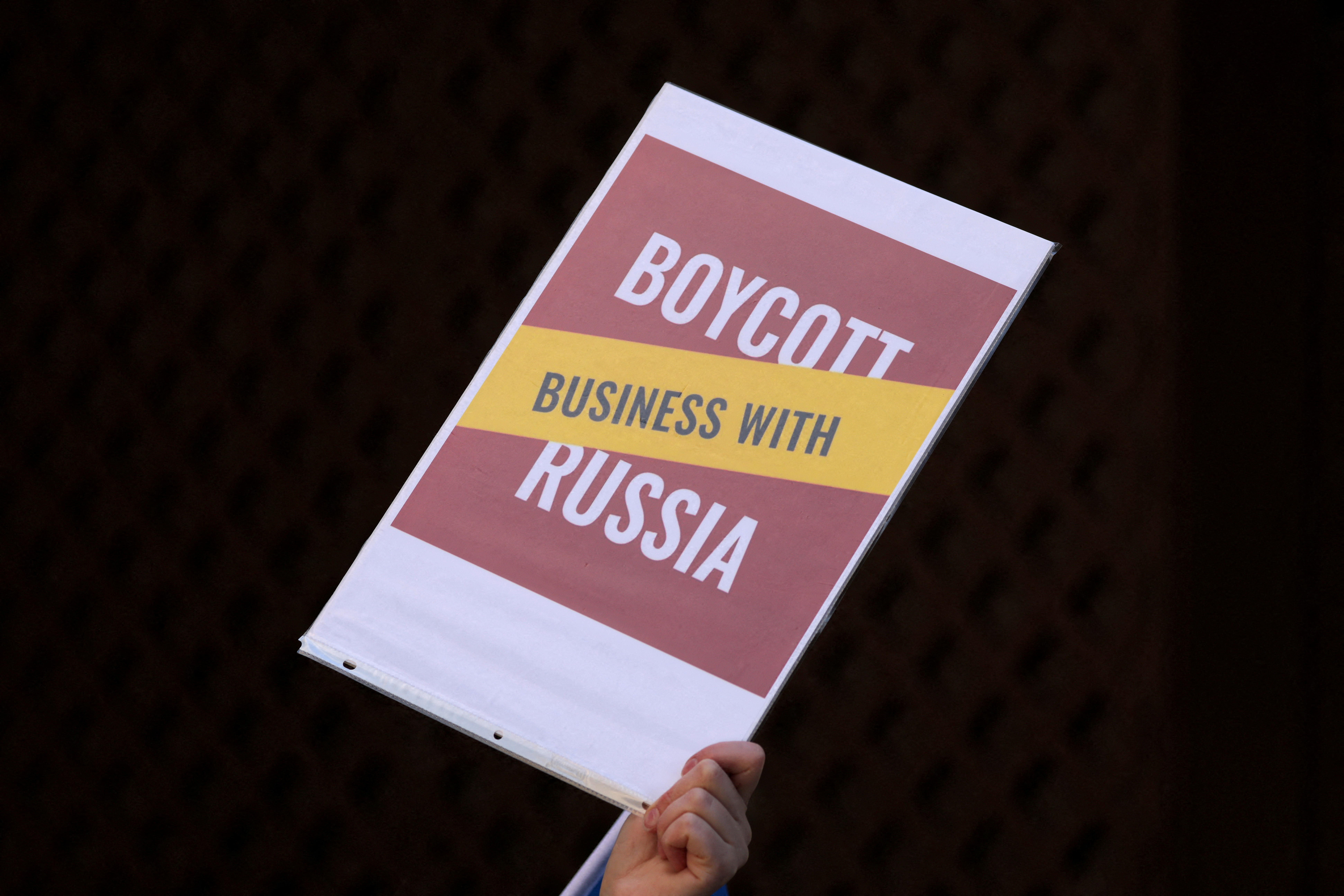 FILE PHOTO: A Ukraine supporter holds a sign on Park Avenue outside the offices of Philip Morris International Inc to protest their continued business in Russia during a demonstration in Manhattan, New York City, April 4, 2022.  REUTERS/Andrew Kelly