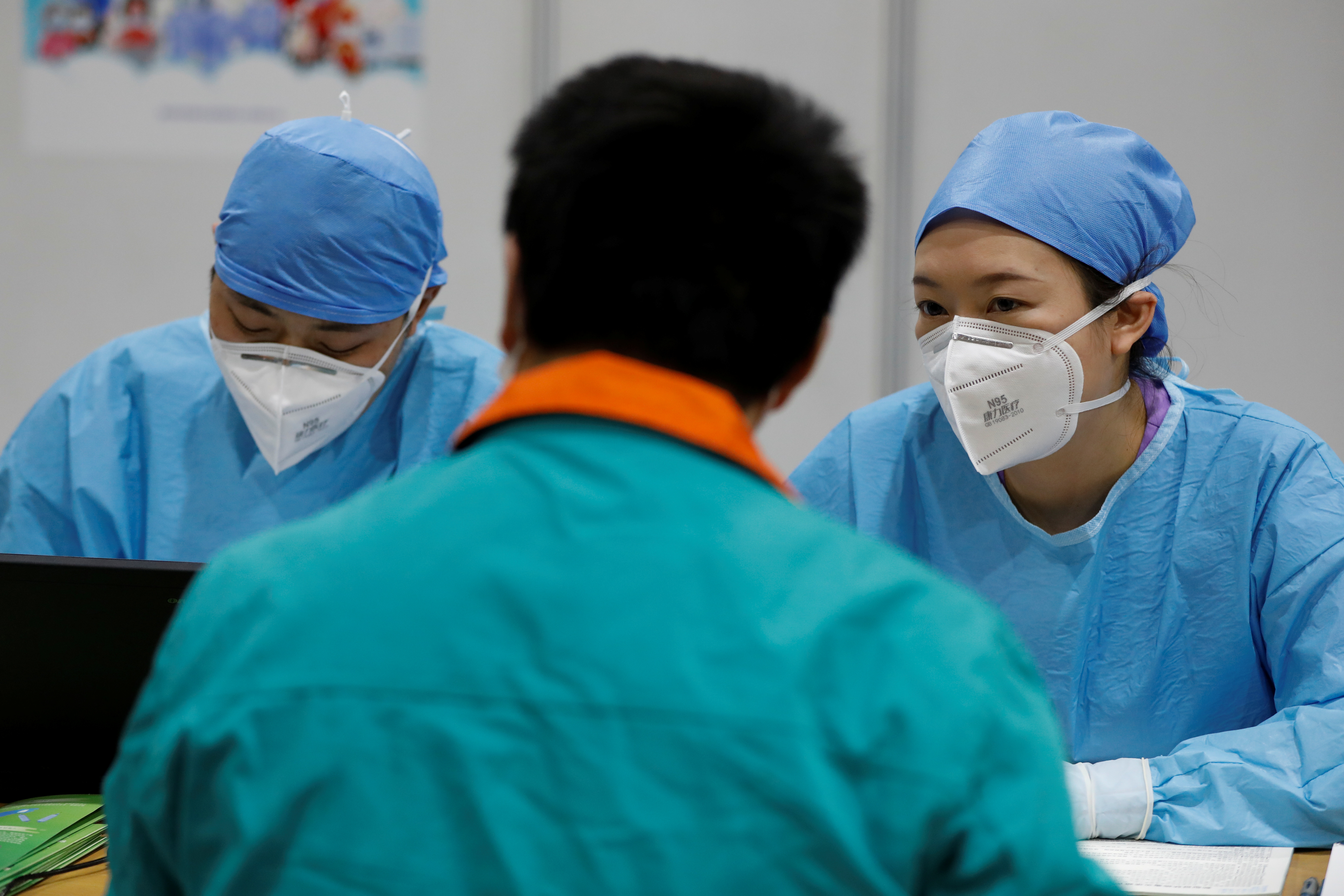 Medical workers speak with a man before he receives a dose of a coronavirus disease (COVID-19) vaccine at a vaccination site, during a government-organized visit, in Beijing, China January 15, 2021. REUTERS/Carlos Garcia Rawlins