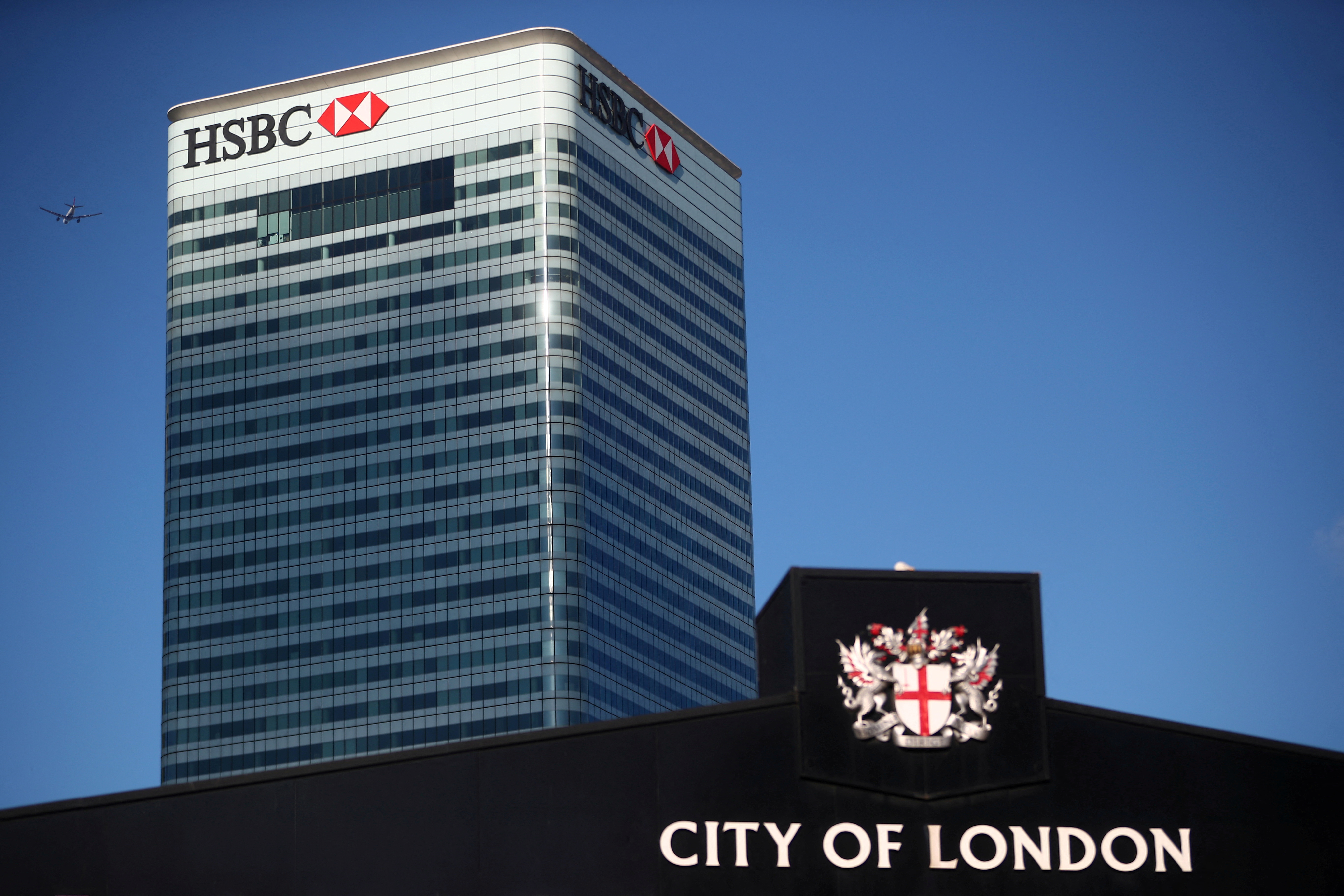 HSBC's building in Canary Wharf is seen behind a City of London sign outside Billingsgate Market in London